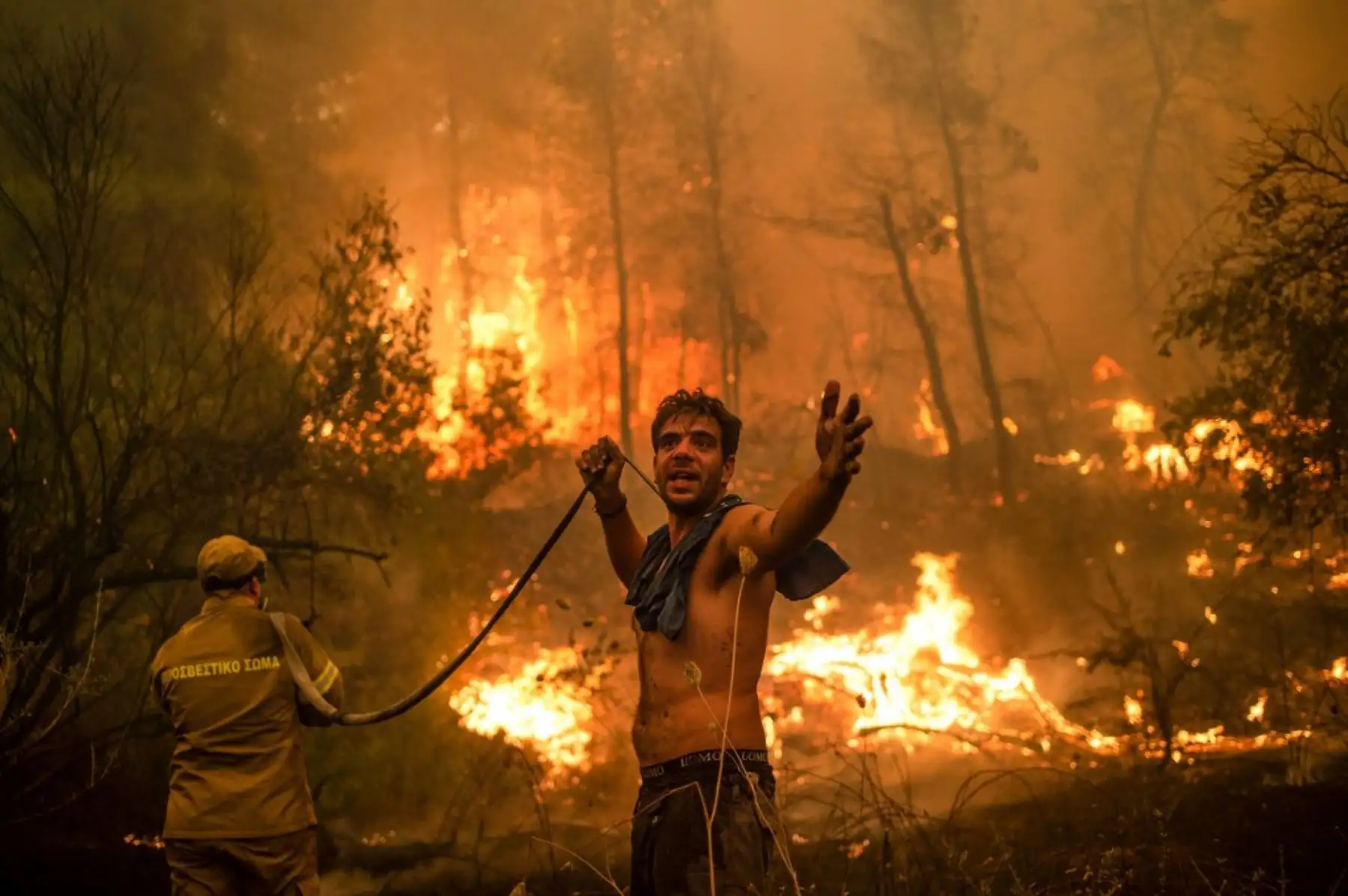 Un residente local hace un gesto mientras sostiene una manguera de agua vacía durante un intento de extinguir los incendios forestales que se acercan al pueblo de Pefki en la isla de Evia (Eubea), Grecia, la segunda isla más grande de Grecia, el 8 de agosto de 2021. Foto: AFP