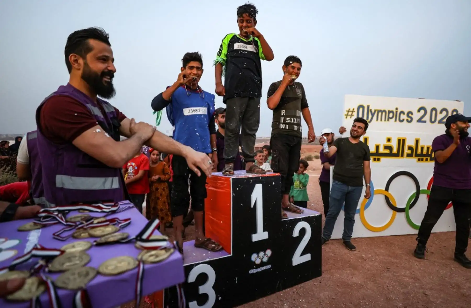 Los niños sirios desplazados suben al podio después de ganar medallas durante los llamados "Juegos Olímpicos del Campamento 2020" en la ciudad de Fuaa, en el noroeste de Siria, el último gran bastión rebelde de Idlib. Foto: AFP