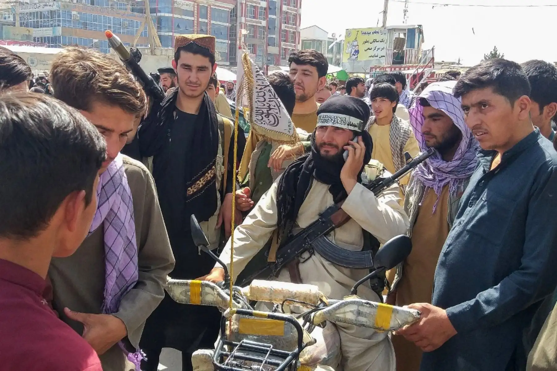El combatiente talibán es visto rodeado por lugareños en Pul-e-Khumri el 11 de agosto de 2021 después de que los talibanes capturaran Pul-e-Khumri, la capital de la provincia de Baghlan, a unos 200 kilómetros al norte de Kabul. Foto: AFP