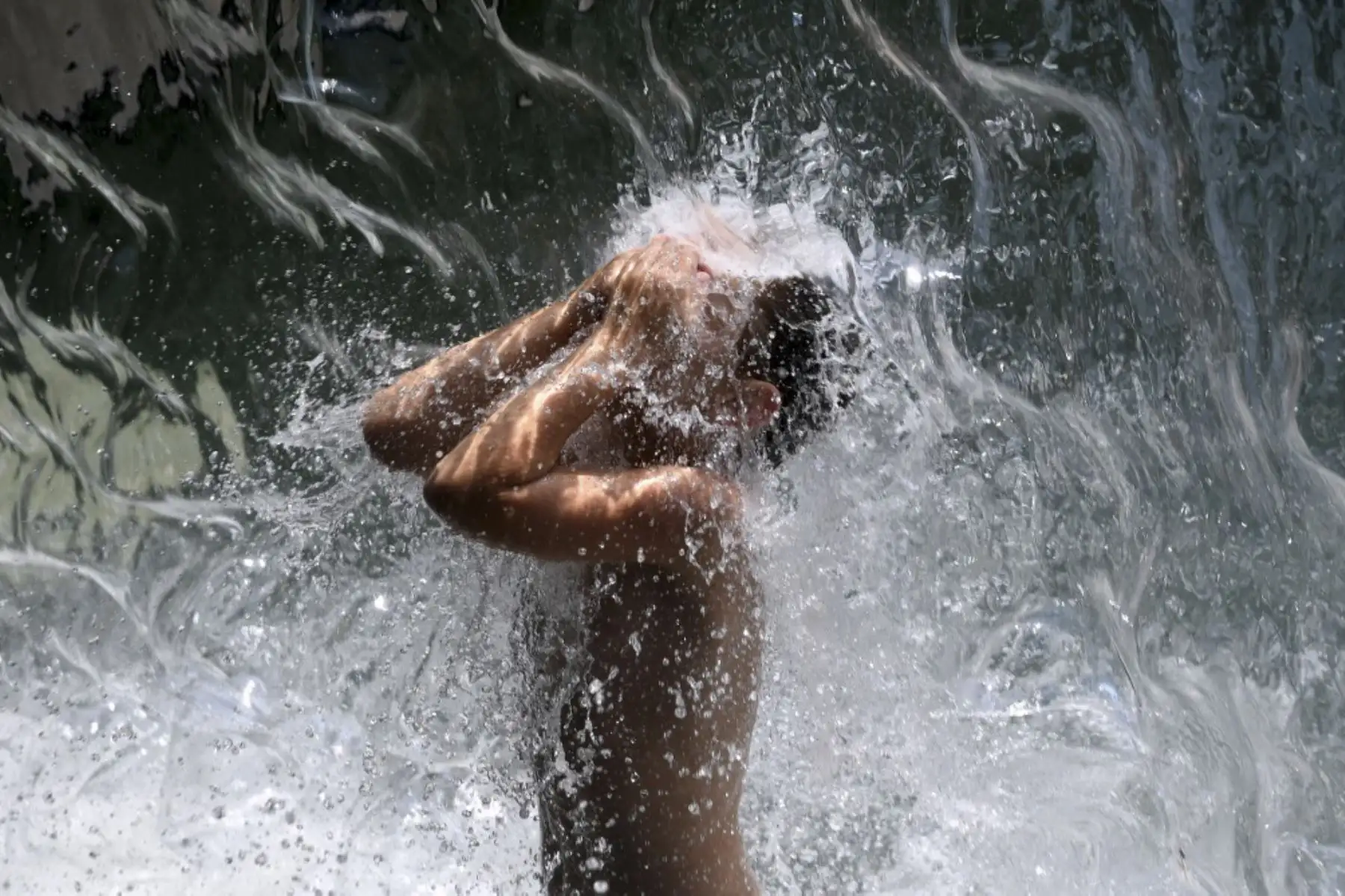 Un niño se refresca en una cascada en Yards Park en Washington, DC, el 12 de agosto de 2021, cuando una ola de calor extremo azota la región. Foto: AFP
