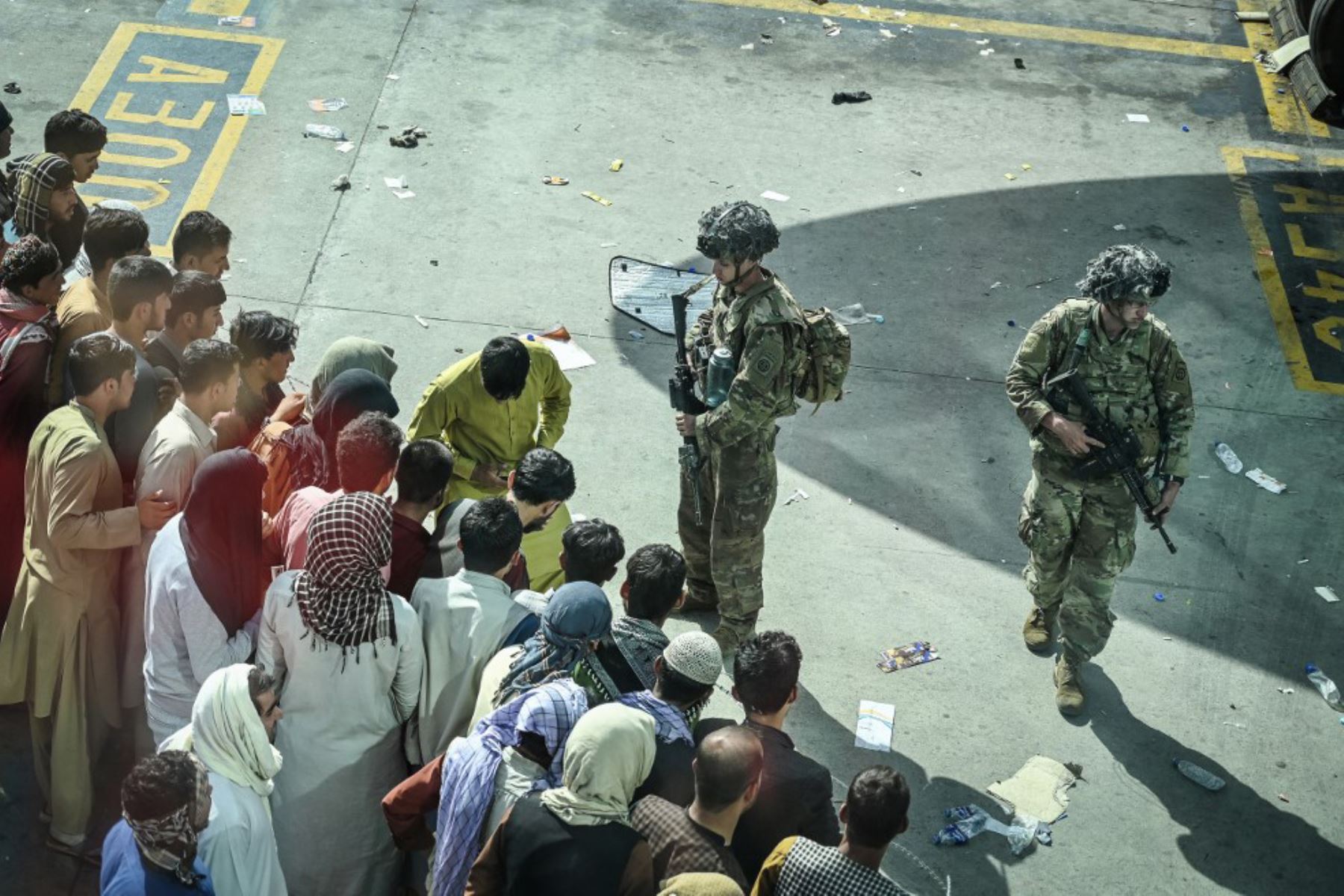 Soldados estadounidenses montan guardia mientras los afganos esperan en el aeropuerto de Kabul, después del final de la guerra de 20 años de Afganistán, mientras miles de personas asaltaban el aeropuerto de la ciudad tratando de huir de la temida línea dura de islamistas del grupo.

Foto: AFP