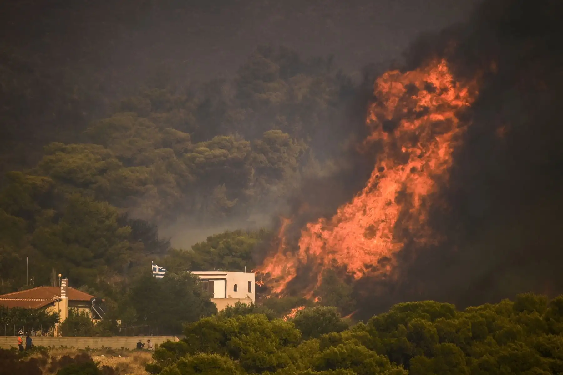 Un incendio forestal arde junto a una casa en el pueblo de Synterina, cerca de Atenas, Grecia. Foto: AFP