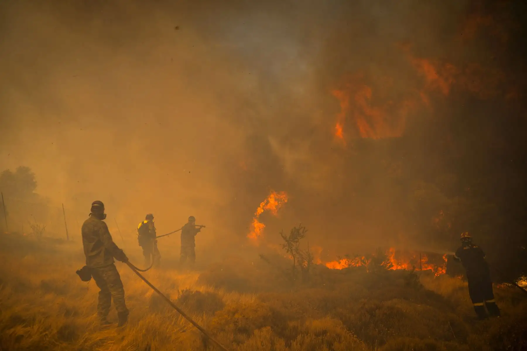 Bomberos y voluntarios utilizan mangueras para extinguir un incendio en el pueblo de Markati, cerca de Atenas, Grecia. Foto: AFP