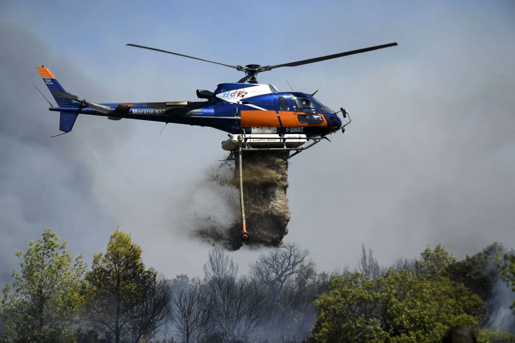 Un Eurocopter AS-350B-3 Ecureuil lanza líquido para extinguir un incendio en Gonfaron, en el departamento francés de Var, en el sur de Francia.
Foto: AFP