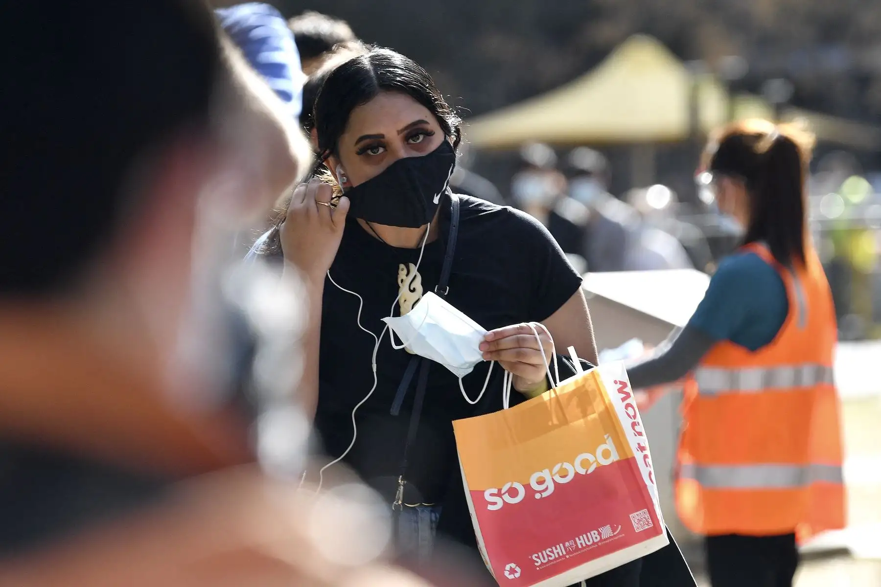 Una niña se ajusta la máscara mientras espera en una cola para la vacunación contra el coronavirus  en Sydney.
Foto: AFP