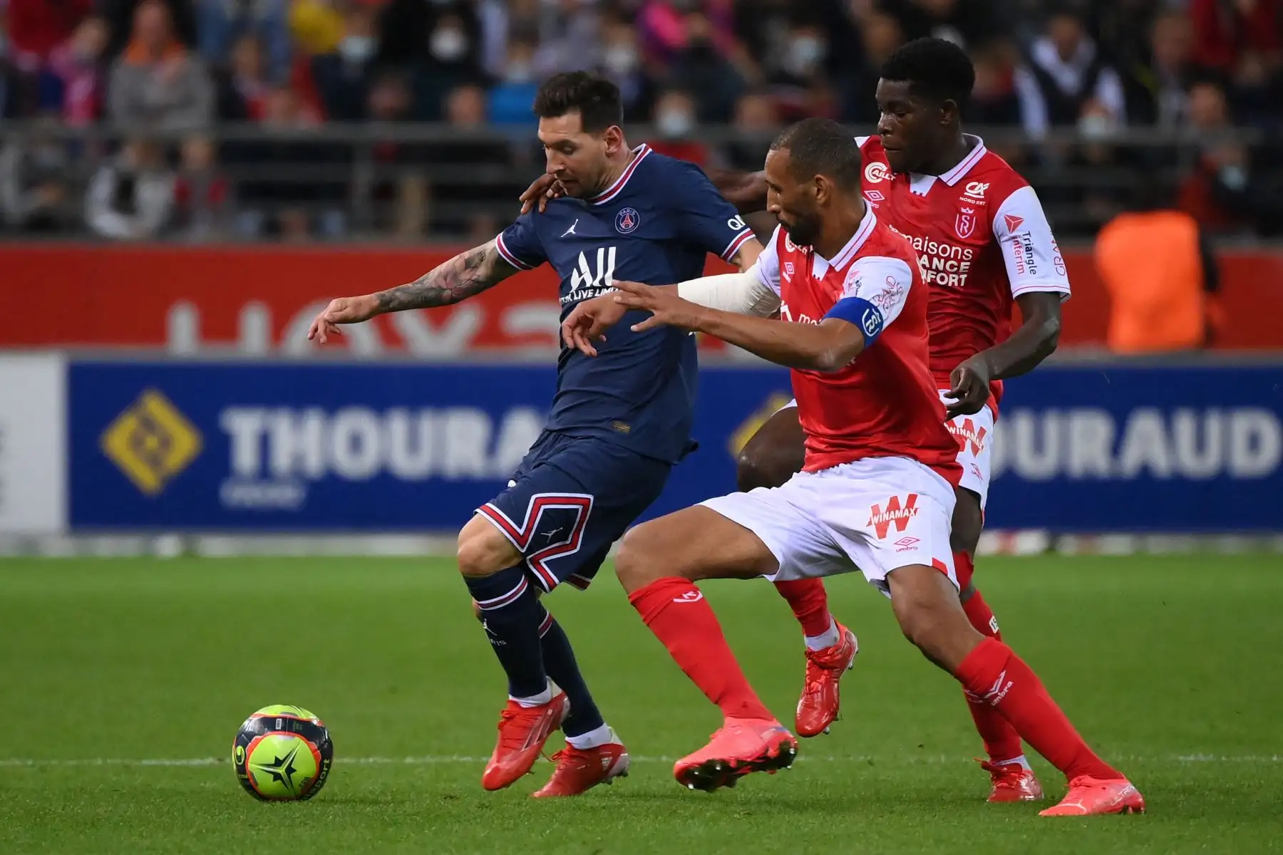 El centrocampista zimbabuense de Reims Marshall Munetsi (R) y el marroquí Yunis Abdelhamid de Reims luchan por el balón con el delantero argentino del Paris Saint-Germain Lionel Messi durante el partido de fútbol francés L1 entre el Stade de Reims y el Paris Saint-Germain en el estadio Auguste Delaune de Reims en 29 de agosto de 2021. Foto: AFP