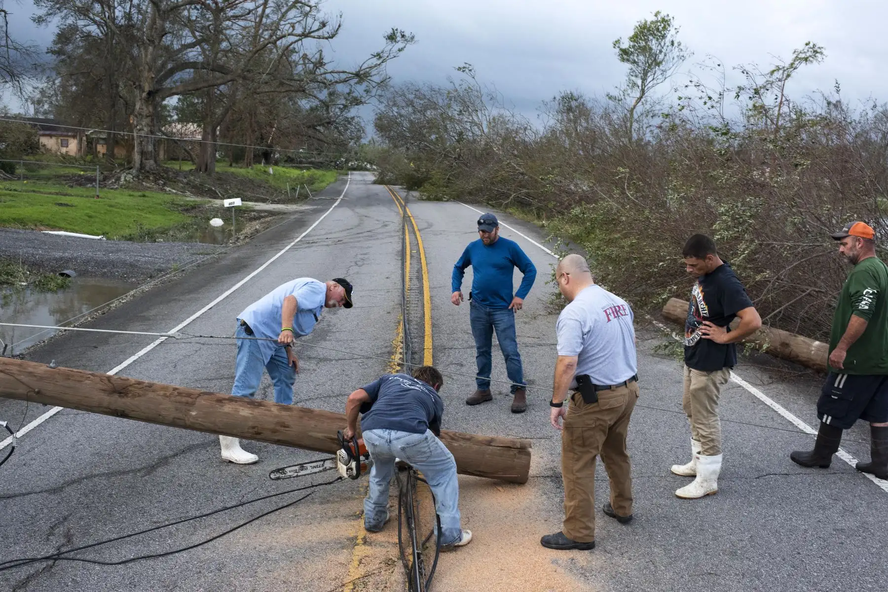 Las personas trabajan juntas para despejar un poste telefónico de la carretera en Bourg, Louisiana, Estados Unidos. Foto: AFP