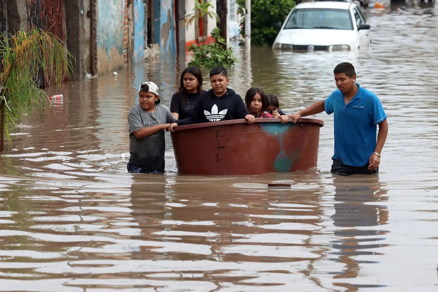 Una familia se desplaza por una calle inundada después de las fuertes lluvias en Tlaquepaque, estado de Jalisco, México. Foto: AFP