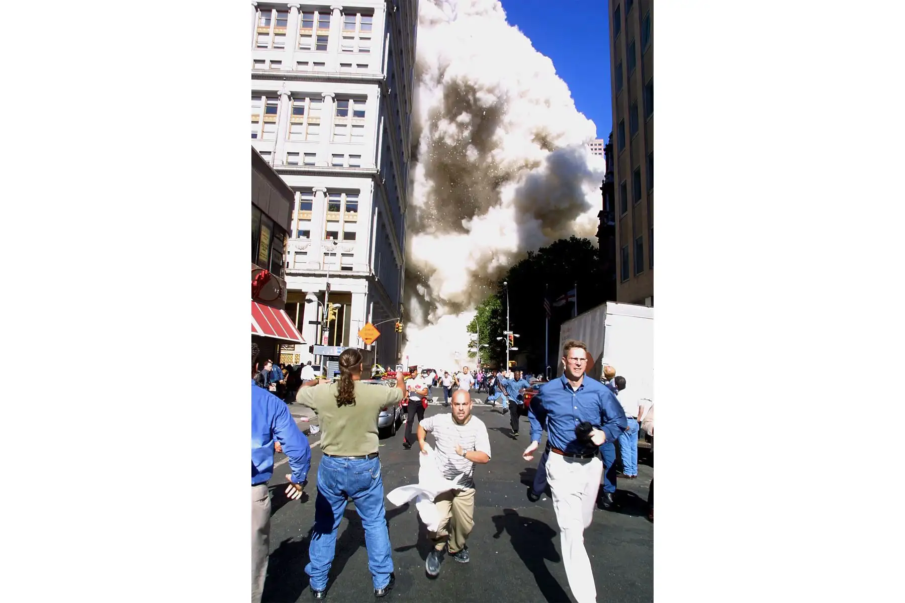 Los peatones huyen del lugar cuando una de las torres del World Trade Center se derrumba el 11 de septiembre de 2001 en Nueva York tras un accidente de avión terrorista en las torres gemelas. 
Foto: AFP