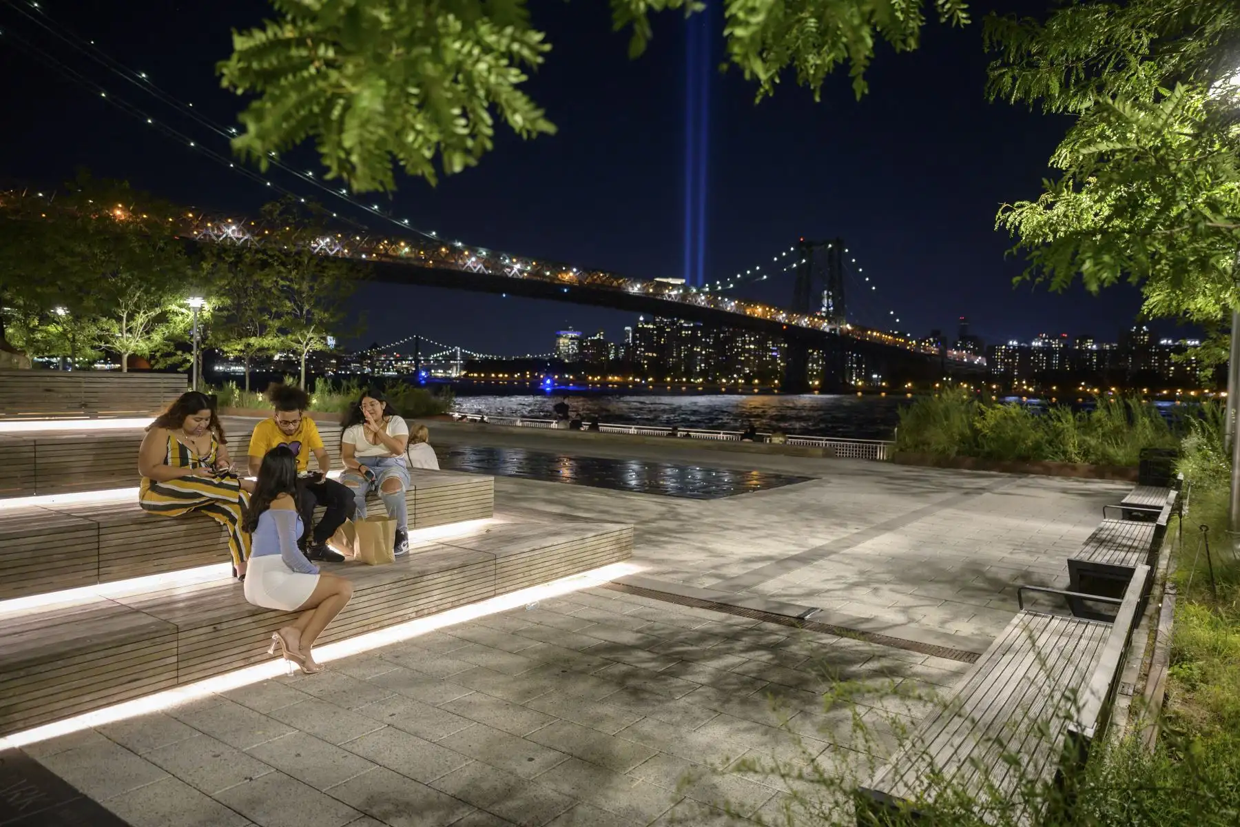 La gente se sienta frente al paseo marítimo de Brooklyn y la instalación 