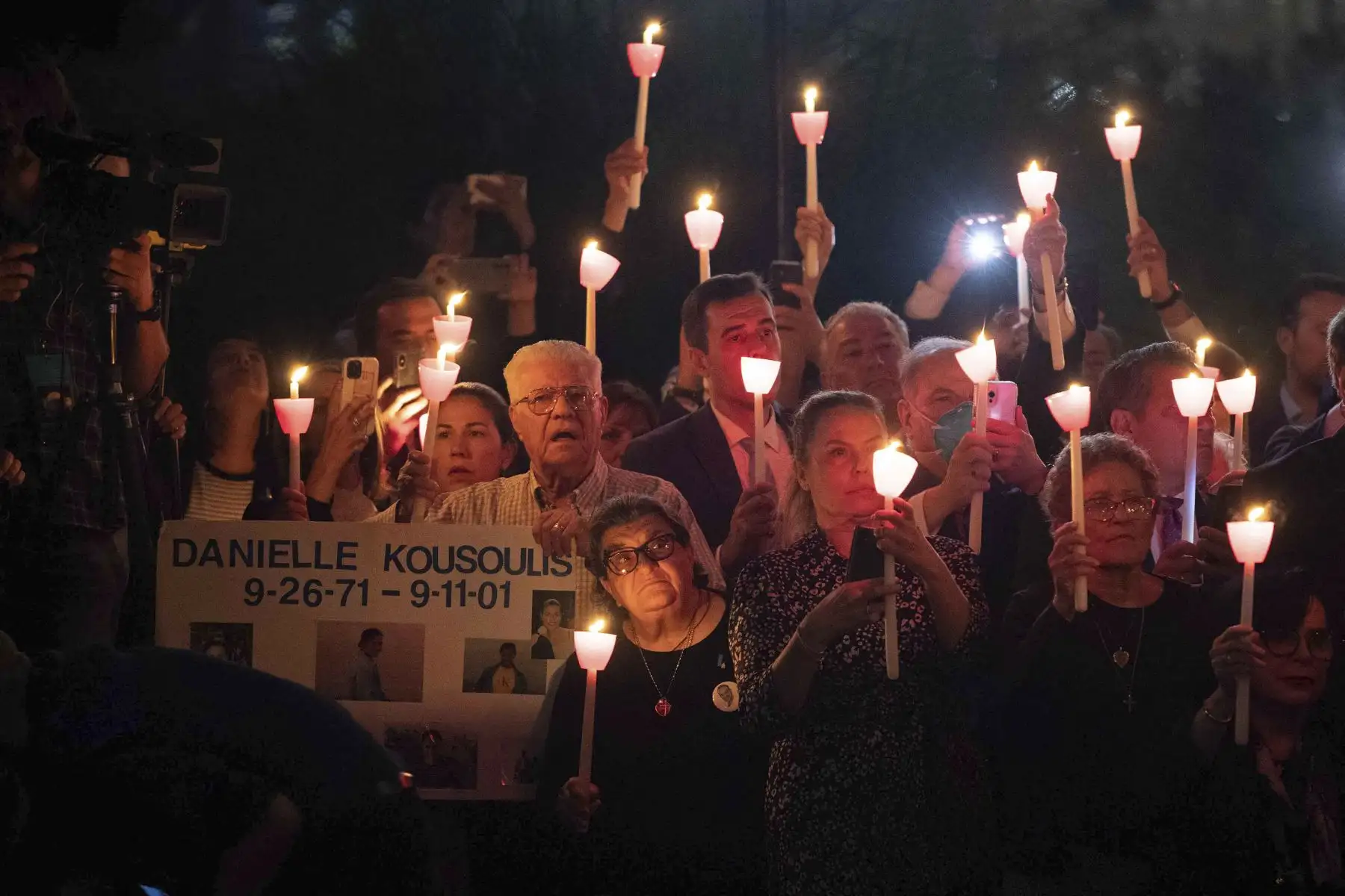 Las personas sostienen velas y un cartel con el nombre de una víctima, mientras asisten a una ceremonia religiosa de conmemoración del 11 de septiembre, en el Santuario Nacional Griego Ortodoxo de San Nicolás, junto al Museo y Memorial del 11-S, en la ciudad de Nueva York. Foto: AFP