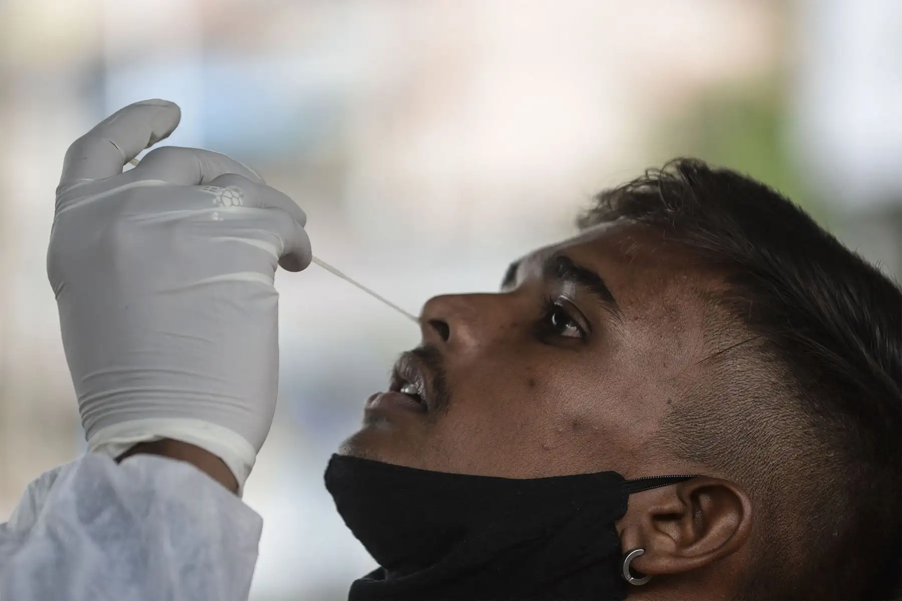 Un personal médico toma una muestra de hisopo de un pasajero para una prueba de reacción en cadena de la polimerasa con transcripción inversa durante una prueba de detección del covid-19 a su llegada a una plataforma ferroviaria en Mumbai.
Foto: AFP