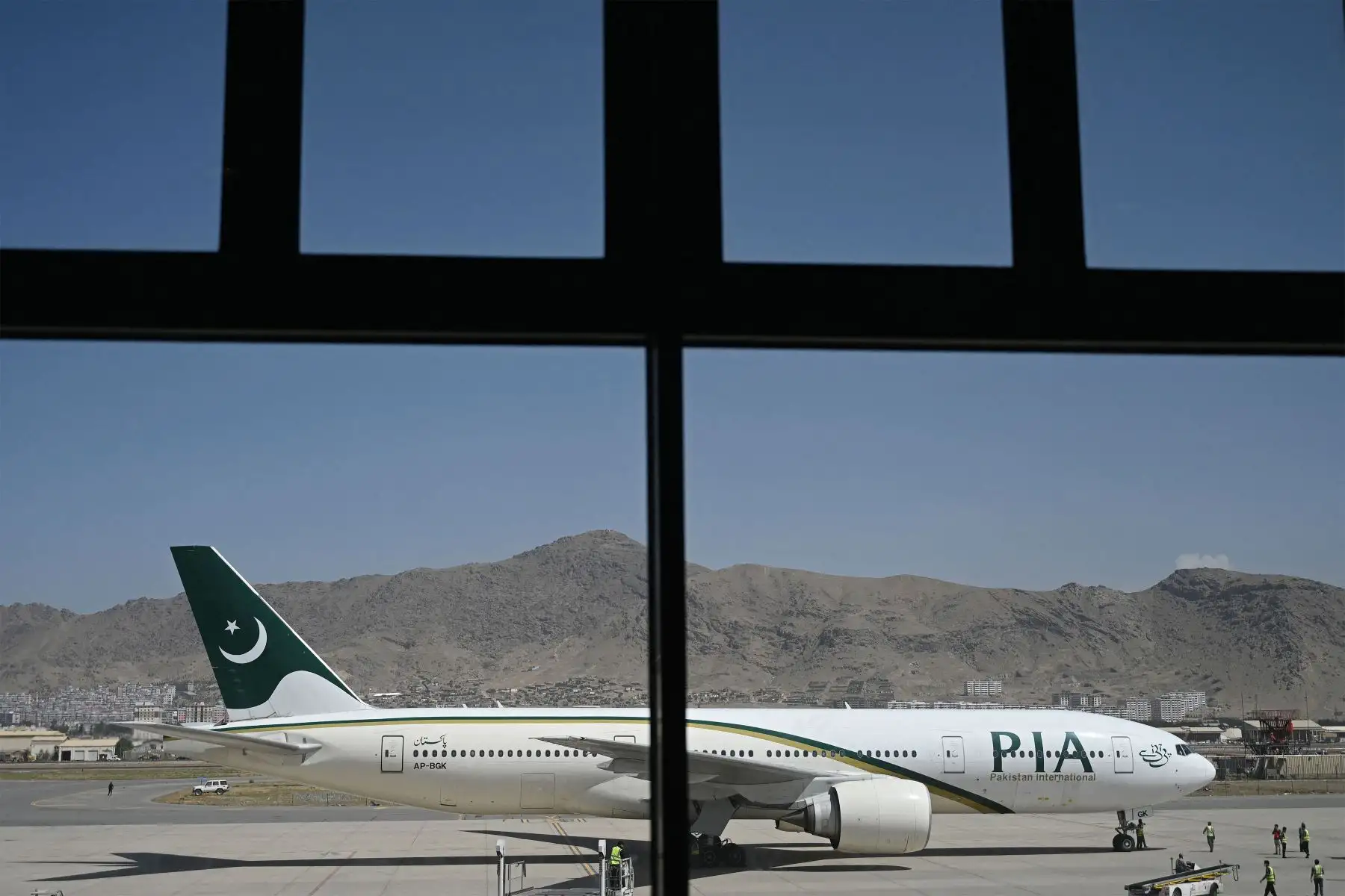 Miembros del personal de tierra están parados en la pista junto a un avión de Pakistan International Airlines , el primer vuelo comercial internacional desde que los talibanes recuperaron el poder el mes pasado, en el aeropuerto de Kabul.
Foto: AFP