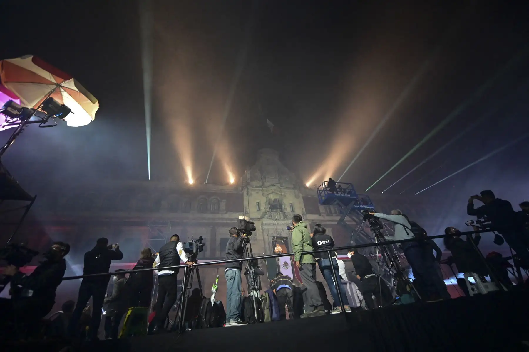 Miembros de los medios de comunicación trabajan mientras el presidente mexicano Andrés Manuel López Obrador y su esposa Beatriz Gutiérrez observan los fuegos artificiales desde el balcón principal del Palacio Nacional. Foto: AFP