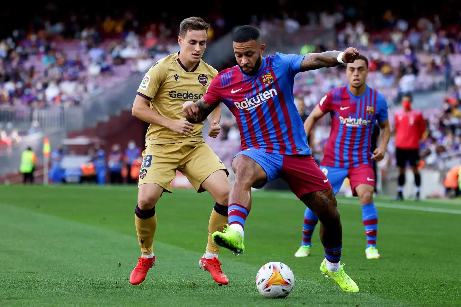 El delantero holandés del Barcelona Memphis Depay disputa el balón ante el extremo del Levante Jorge De Frutos durante el partido de la séptima jornada de LaLiga Santander, en el estadio Camp Nou. Foto: EFE