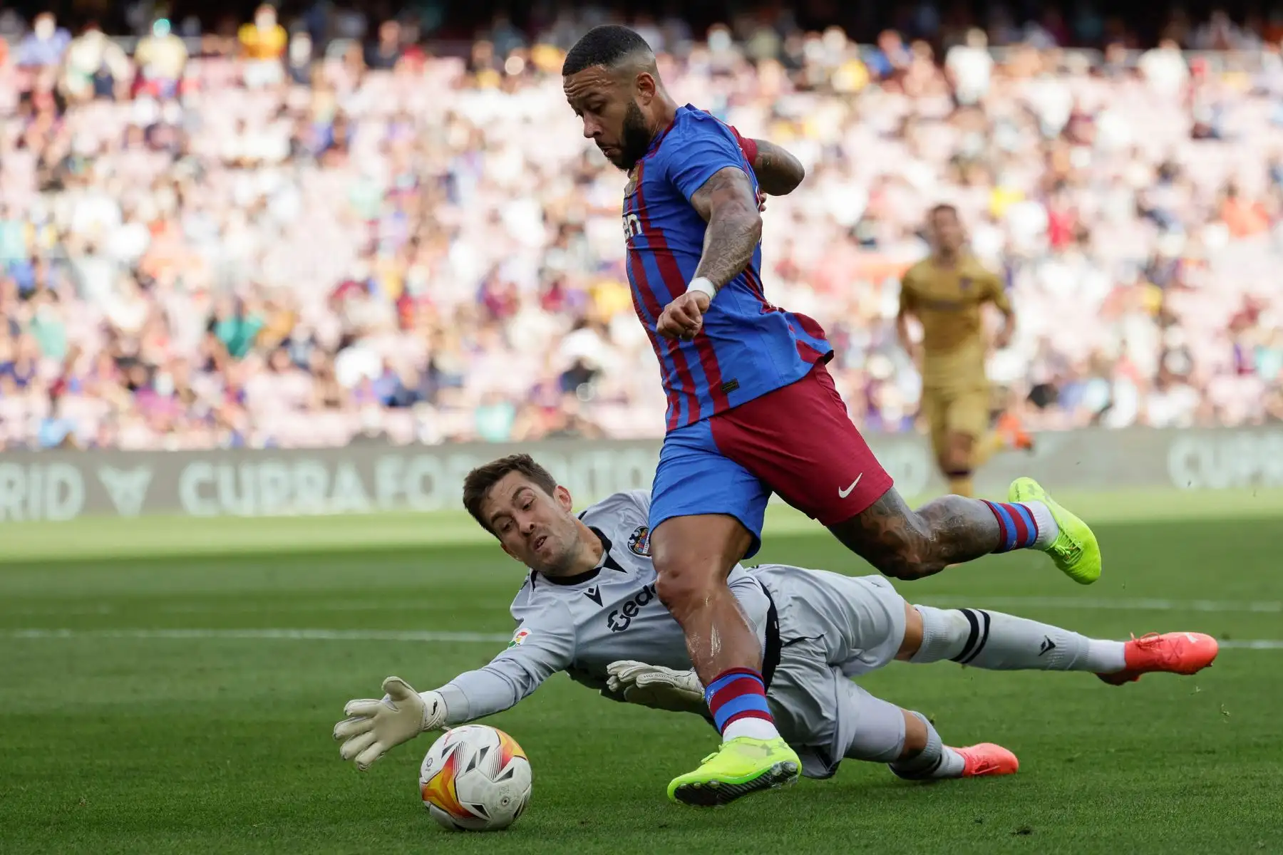 El delantero holandés del Barcelona Memphis Depay trata de marcar ante el portero del Levante Aitor Fernández durante el partido por la séptima jornada de LaLiga Santander, en el estadio Camp Nou. Foto: EFE