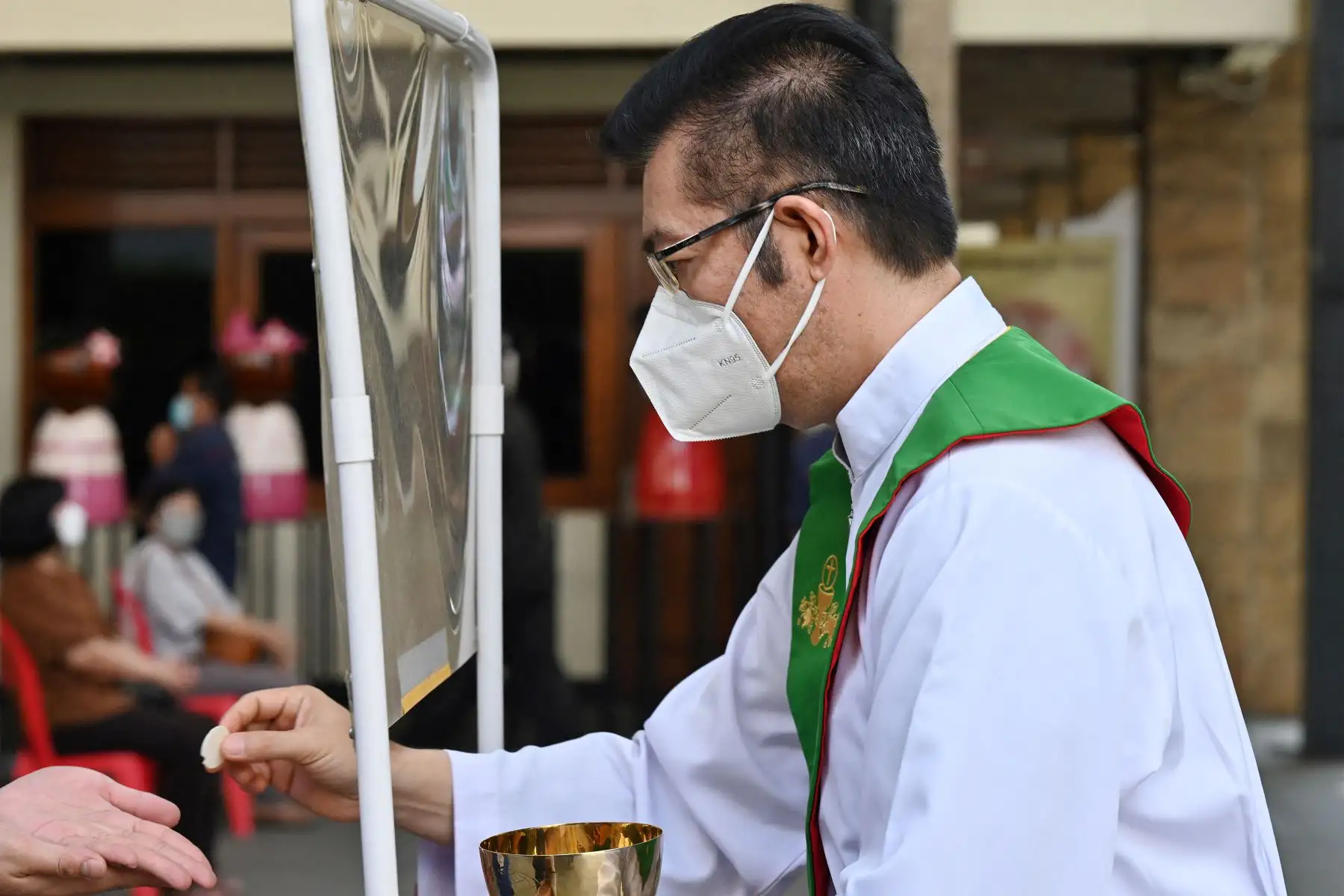 Un hombre recibe una hostia de comunión detrás de una pantalla mientras las personas asisten a las oraciones mientras observan las medidas de prevención contra el coronavirus, en una catedral de Yakarta.
Foto: AFP
