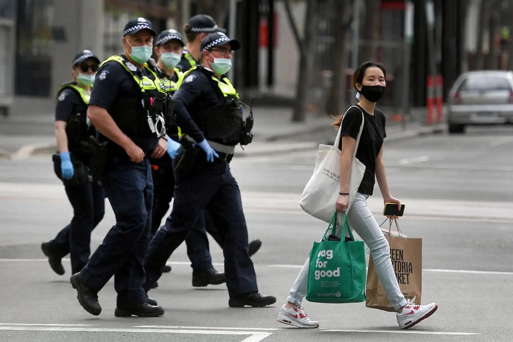 Una mujer cruza la calle con sus compras mientras la policía patrulla por las calles de Melbourne, mientras la ciudad lidia con un aumento en las infecciones por covid-19, registrando 950 casos en el total diario más grande desde el inicio de la pandemia.
Foto: AFP