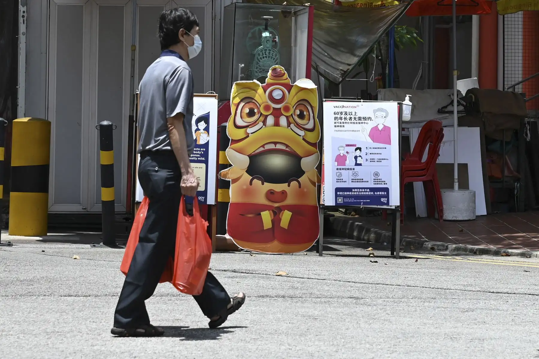 Un hombre pasa junto a un tablero de notificaciones con información sobre las vacunas contra el coronavirus, en el distrito de Chinatown, en Singapur. Foto: AFP