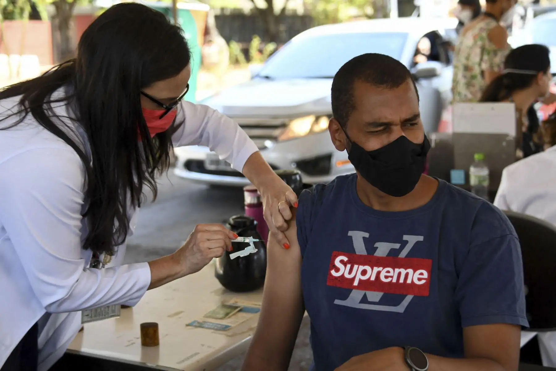 Un hombre reacciona cuando recibe una inyección de la vacuna CoronaVac COVID-19 de un trabajador de la salud en un puesto de vacunación de autoservicio en Brasilia. Foto: AFP