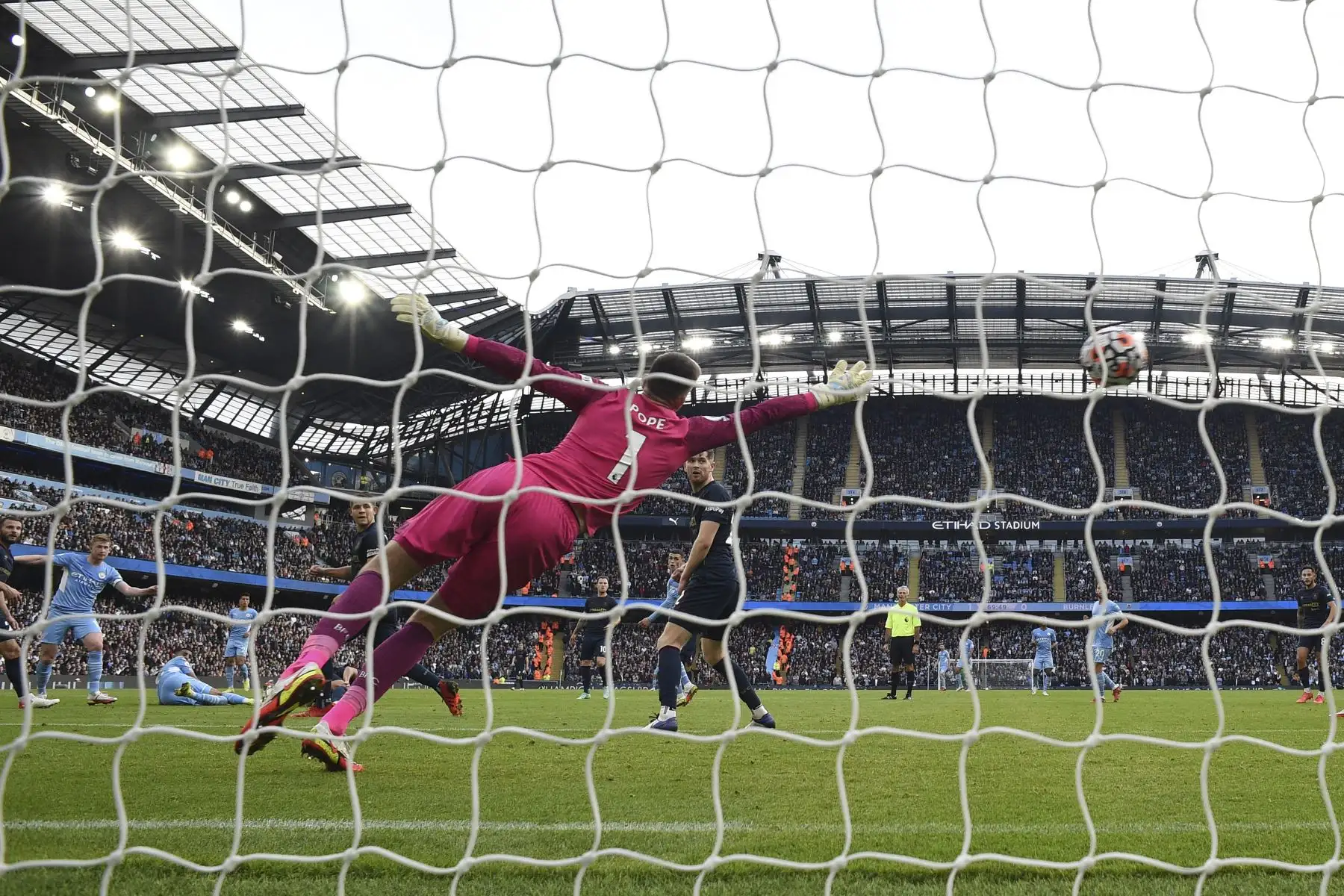 El portero inglés del Burnley Nick Pope se lanza para atajar un disparo del centrocampista belga del Manchester City Kevin De Bruyne durante el partido de fútbol de la Premier League. Foto: AFP