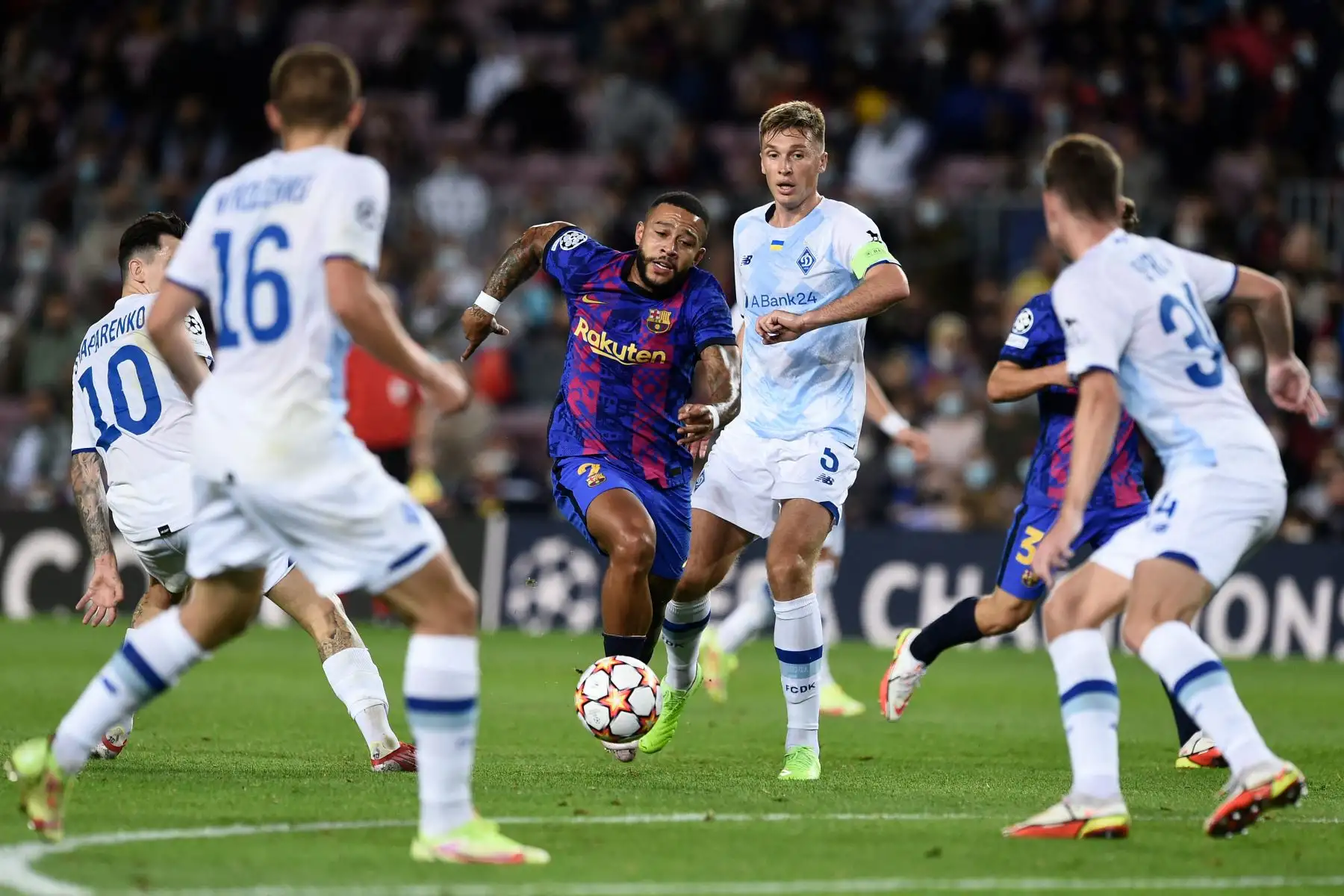 El delantero holandés del Barcelona Memphis Depay  compite con el centrocampista ucraniano del Dynamo Kiev Serhiy Sydorchuk durante el partido de fútbol del Grupo E de la Liga de Campeones de la UEFA entre el FC Barcelona y el Dynamo de Kiev en el estadio Camp Nou de Barcelona. Foto: AFP