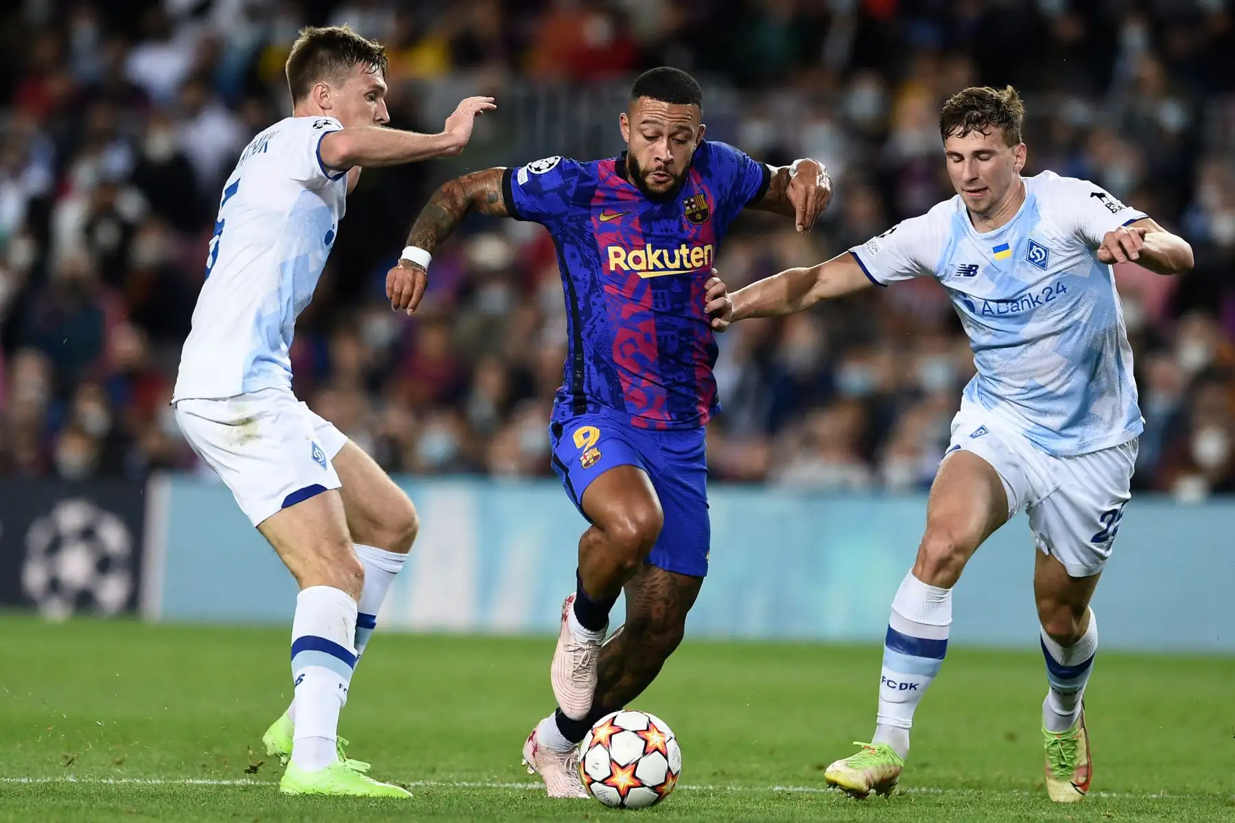 El delantero holandés del Barcelona Memphis Depay  compite con el centrocampista ucraniano del Dynamo Kiev Serhiy Sydorchuk durante el partido de fútbol del Grupo E de la Liga de Campeones de la UEFA entre el FC Barcelona y el Dynamo de Kiev en el estadio Camp Nou de Barcelona. Foto: AFP