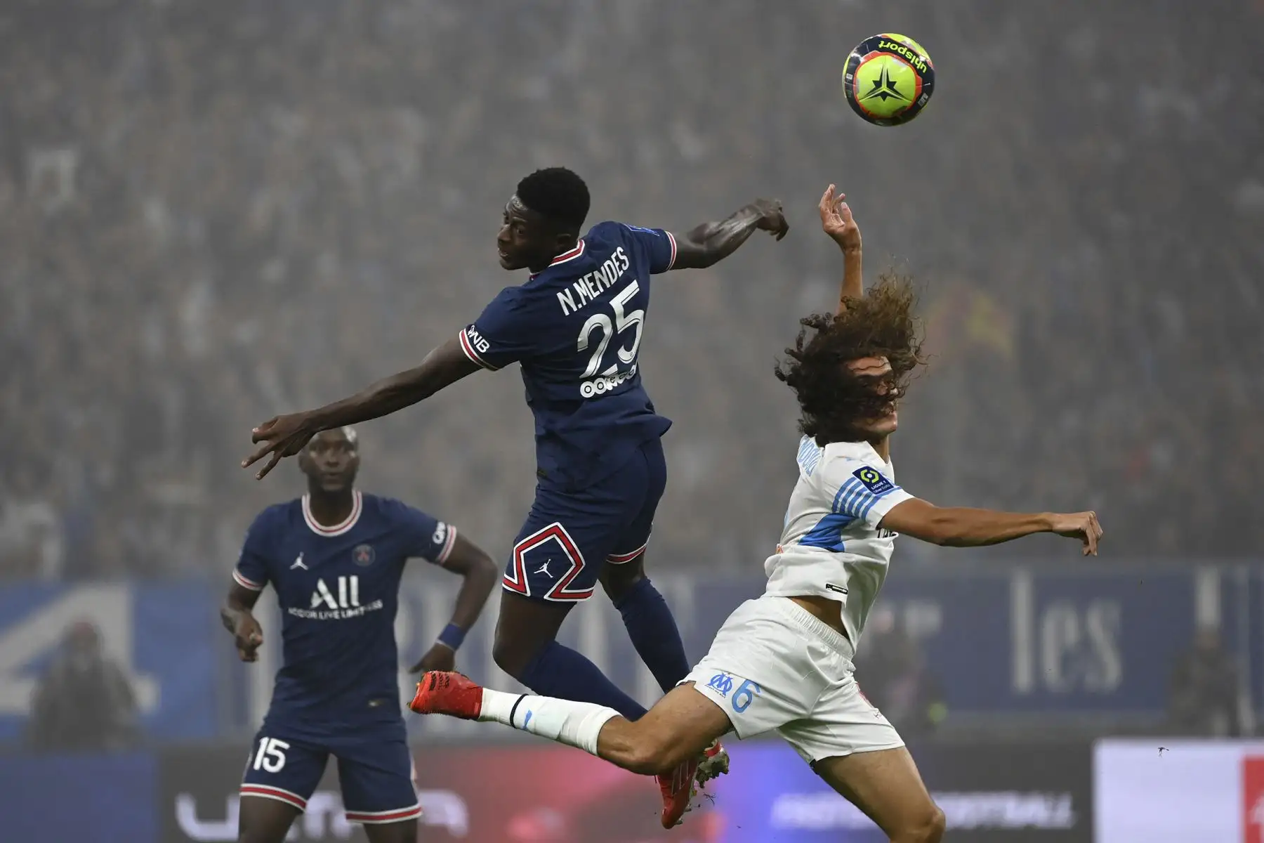El defensor portugués del Paris Saint-Germain Nuno Mendes encabeza el balón junto al defensor francés del Marsella Matteo Guendouzi durante el partido del fútbol francés. Foto: AFP