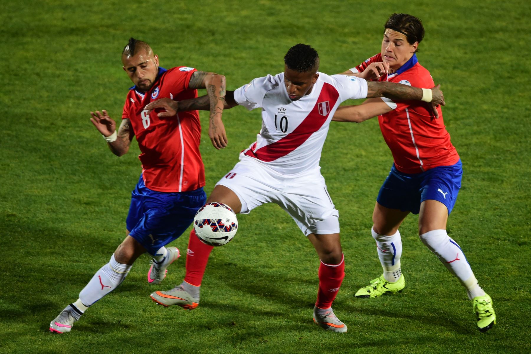 El delantero peruano Jefferson Farfán (C) compite por el balón con el mediocampista chileno Arturo Vidal (L) y el defensor Eugenio Mena durante la semifinal del campeonato de fútbol de la Copa América 2015, en Santiago, el 29 de junio de 2015.
Foto: AFP