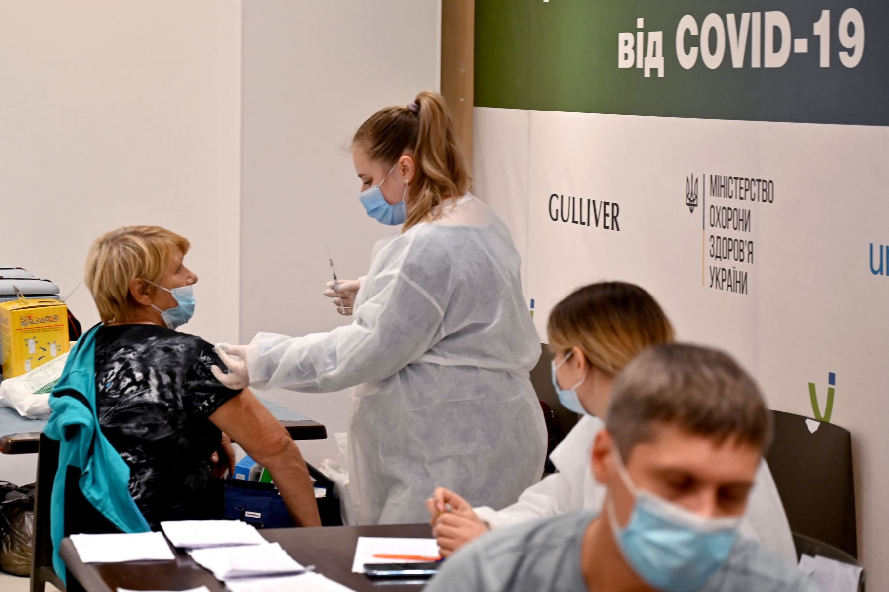 Un paciente recibe una dosis de la vacuna contra el coronavirus en un centro de vacunación temporal dentro de un centro comercial en Kiev, bajo la presión de las autoridades que introdujeron restricciones adicionales en las regiones más afectadas por una nueva ola epidémica.Foto: AFP