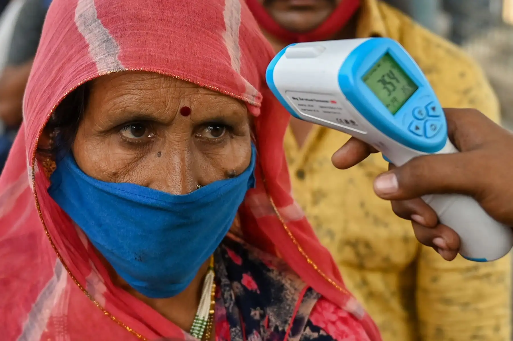 Un trabajador de la salud controla la temperatura de los pasajeros durante una prueba de detección del coronavirus Covid-19 en una plataforma ferroviaria en Mumbai.
Foto: AFP