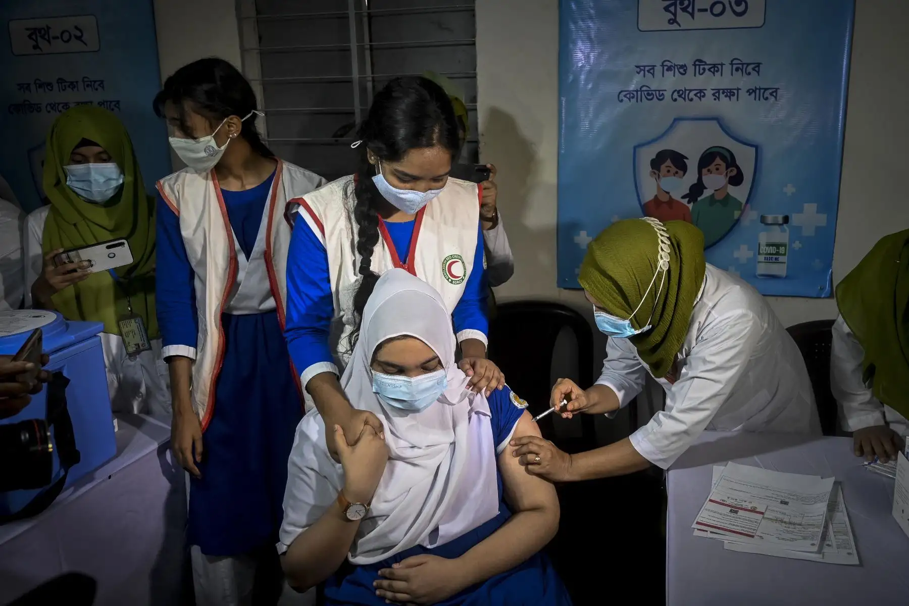 Un trabajador de la salud vacuna a un estudiante contra la Covid-19 dentro de las instalaciones de una escuela en Dhaka. Foto: AFP