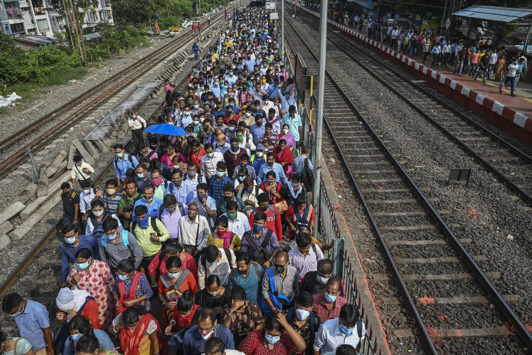 Viajeros caminan a lo largo de una plataforma ferroviaria después de salir de un tren local suburbano en Calcuta. Foto: AFP