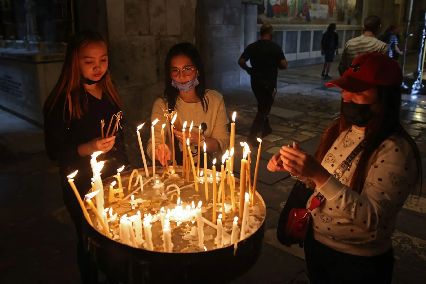 Los creyentes encienden velas en la Iglesia del Santo Sepulcro en la Ciudad Vieja de Jerusalén, cuando Israel reabre a los turistas vacunados contra el Covid-19. Foto: AFP