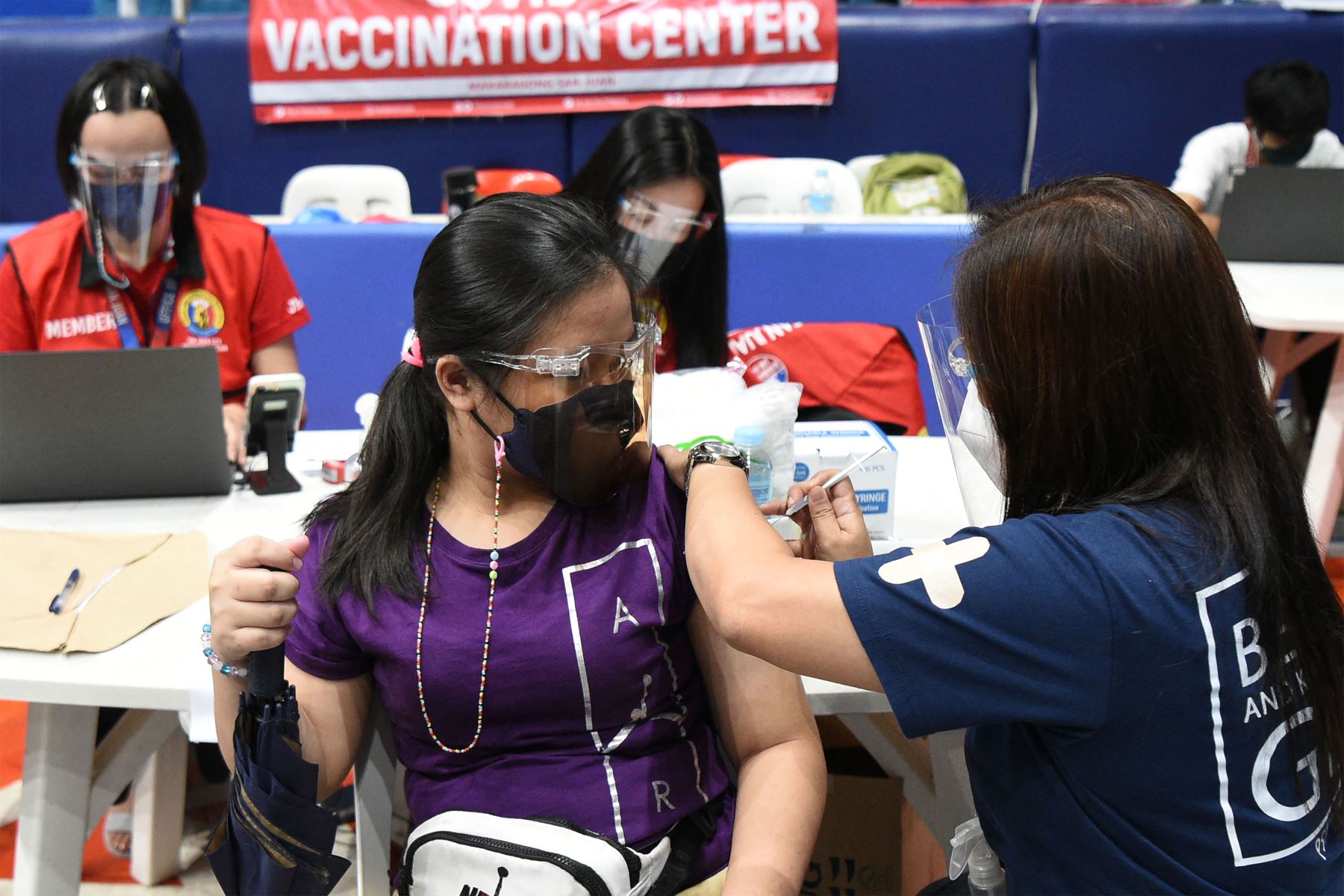 Una adolescente recibe una vacuna contra el coronavirus BioNtech-Pfizer covid-19 durante la inoculación de la población de 12 a 17 años en un estadio de la ciudad de San Juan, suburbano de Manila.
Foto: AFP