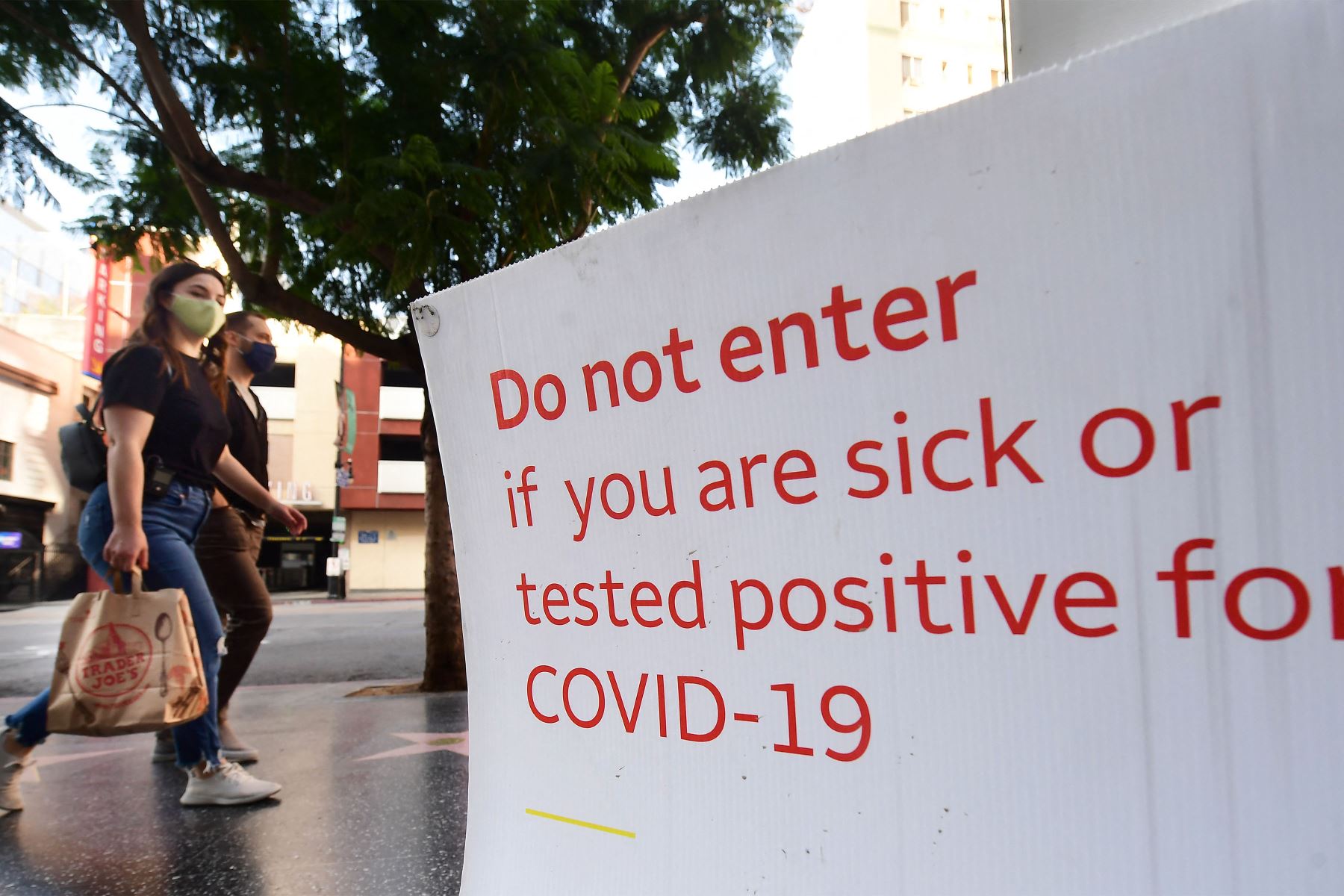 Los peatones con mascarillas pasan frente a un letrero que indica los requisitos de Covid-19 frente a una tienda en Hollywood, California.
Foto : AFP