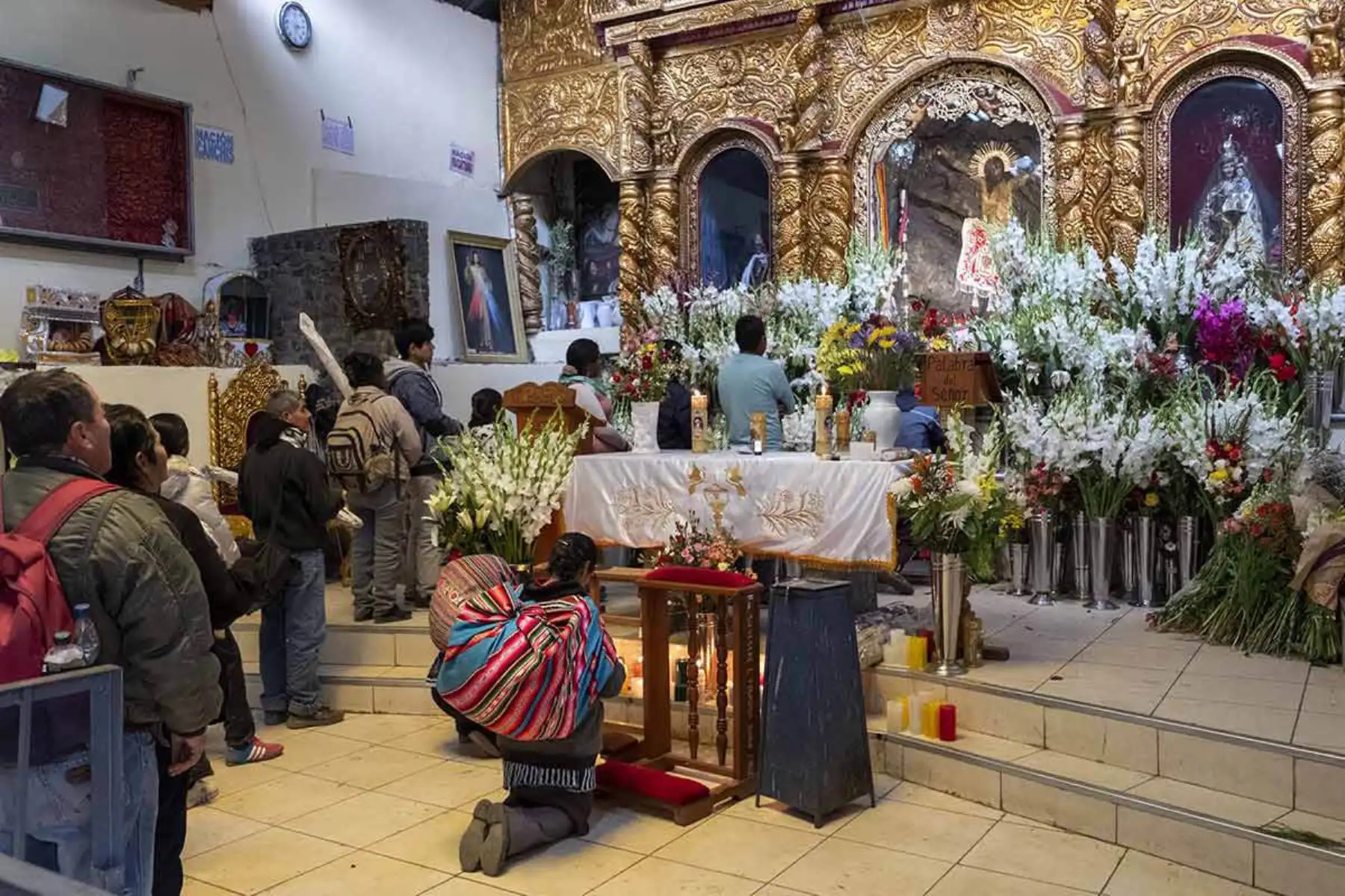 Devotos llegan a los pies de la pintura grabada en la enorme roca cubierta por el retablo. Fotografía del libro, Qoyllurit