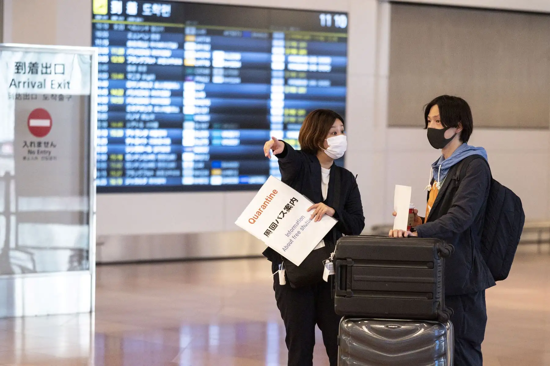 Un pasajero que llega desde el extranjero es recibido por un agente de cuarentena en la sala de llegadas del aeropuerto de Haneda en Tokio.
Foto: AFP