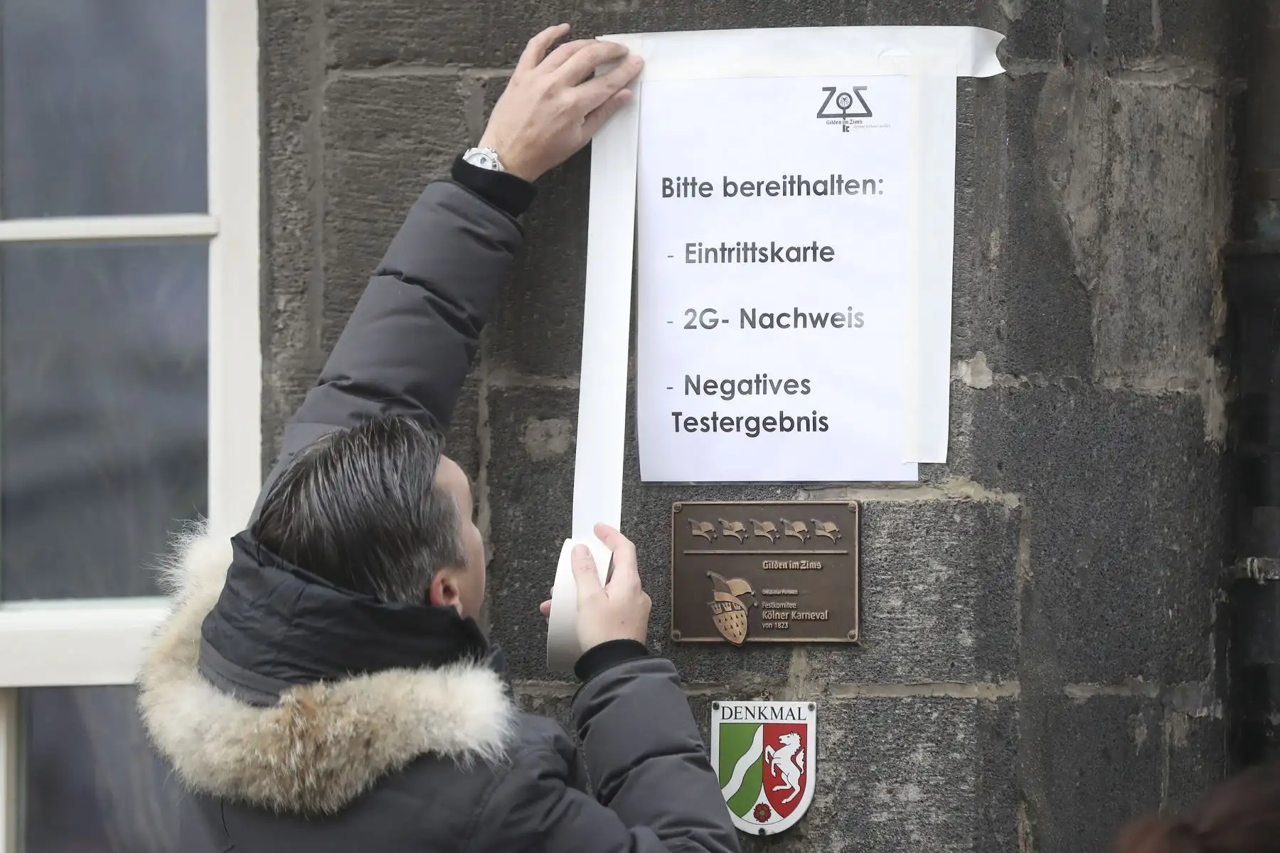 Un empleado de un bar coloca un cartel con las normas covid-19 en Colonia, Alemania. Foto: EFE