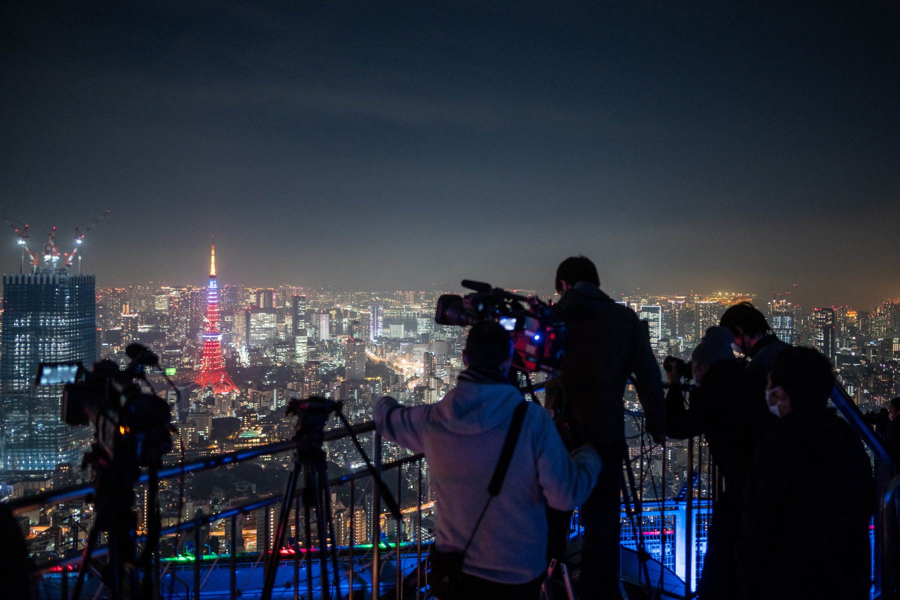 La gente observa el cielo nocturno con un telescopio mientras fotógrafos y videoperiodistas documentan un eclipse lunar desde la plataforma de observación de Roppongi Hills en Tokio. Foto: AFP