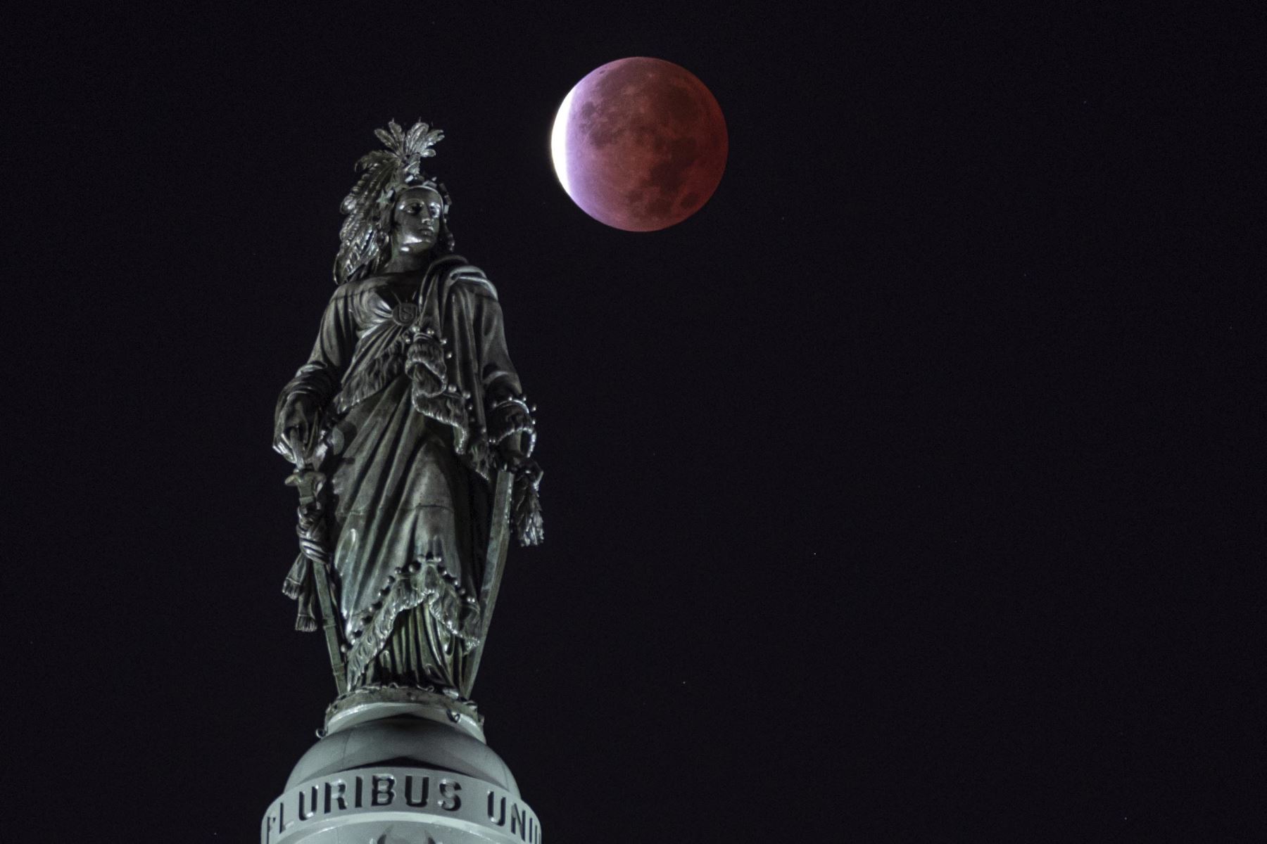 La luna, con un eclipse lunar parcial, se ve detrás de la Estatua de la Libertad, en el Capitolio en Washington. Foto: AFP