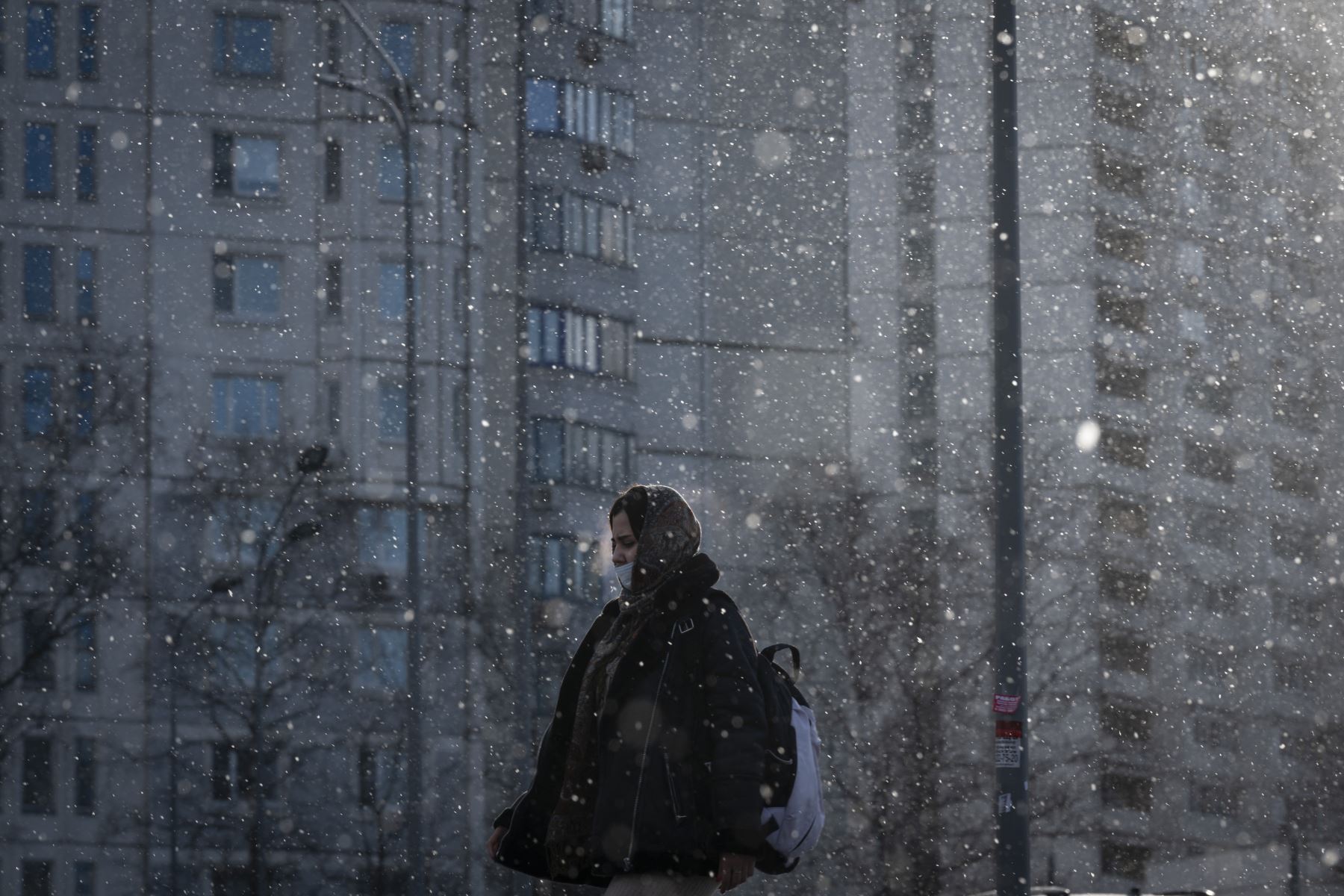 Una mujer que usa una mascarilla pasa junto a edificios residenciales durante una nevada en Moscú. Foto: AFP