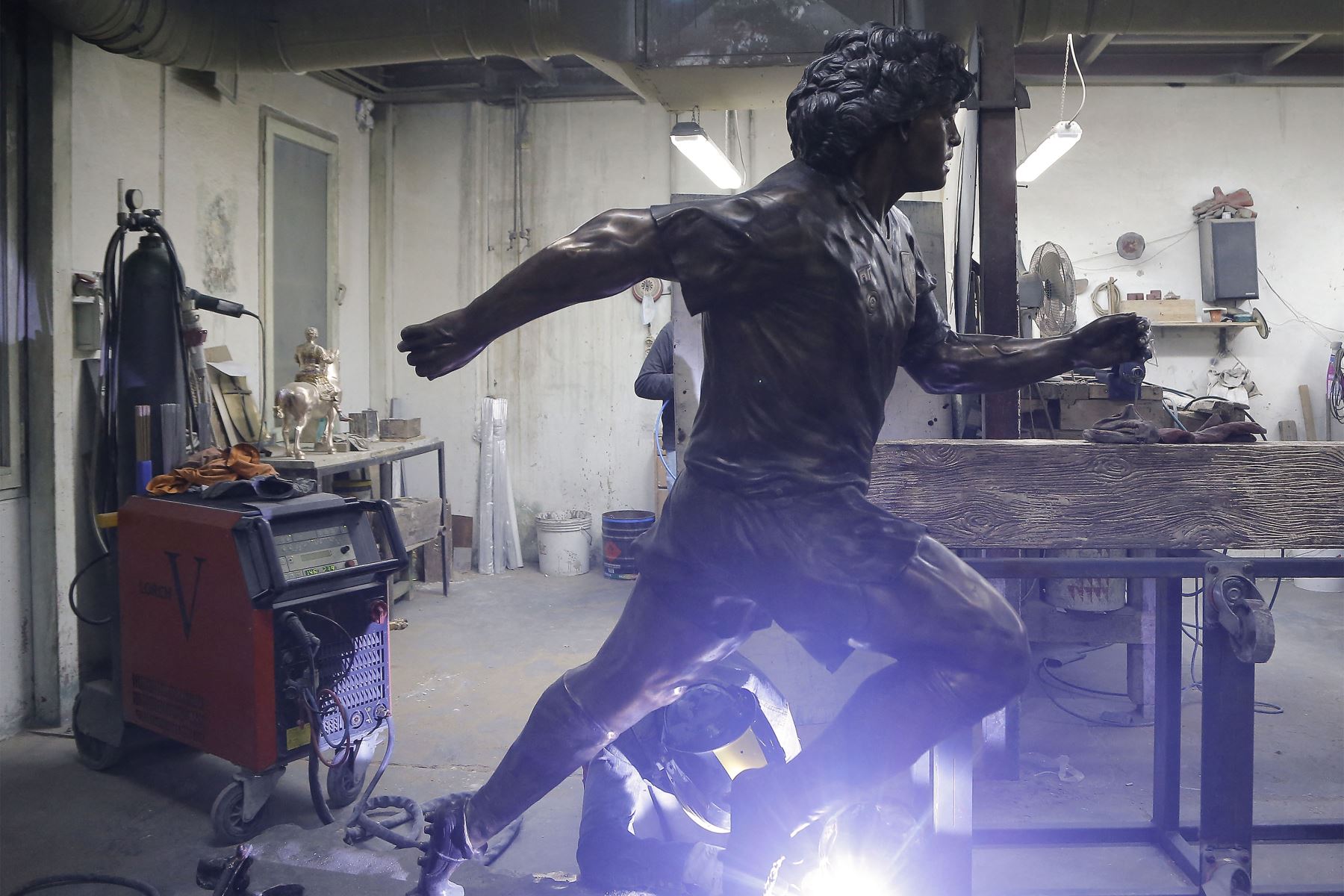 Un soldador trabaja en una estatua de bronce de tamaño natural del fallecido leyenda del fútbol argentino Diego Armando Maradona, en el estudio del escultor italiano Domenico Sepe en Nápoles. 
Foto: AFP