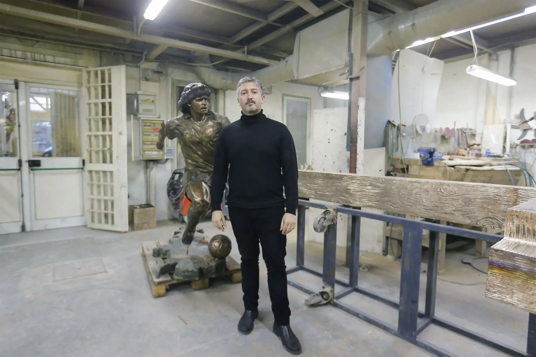 Un soldador trabaja  mientras el escultor italiano Domenico Sepe toca una estatua de bronce de tamaño natural del fallecido leyenda del fútbol argentino Diego Armando Maradona,  en su estudio en Nápoles. 
Foto: AFP