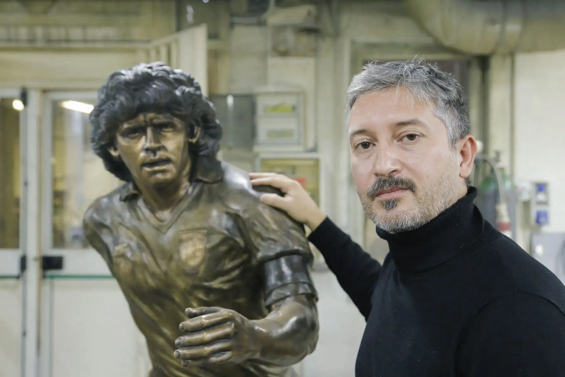 Un soldador trabaja  mientras el escultor italiano Domenico Sepe toca una estatua de bronce de tamaño natural del fallecido leyenda del fútbol argentino Diego Armando Maradona,  en su estudio en Nápoles. 
Foto: AFP