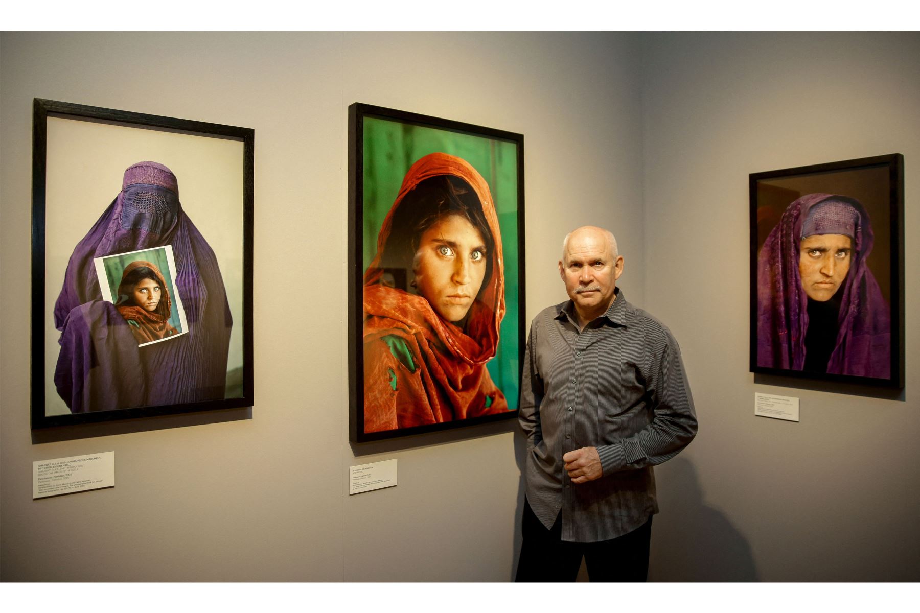 El fotógrafo estadounidense Steve McCurry posa junto a sus fotos de la "niña afgana" llamada Sharbat Gula en la inauguración de la exposición "Abrumados por la vida" de su trabajo en el Museo de Arte y Comercio de Hamburgo, en el norte de Alemania.
Foto: AFP