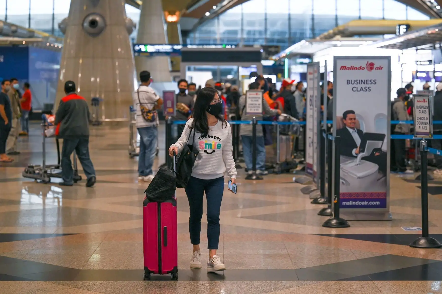 Una pasajera usa una mascarilla mientras camina en el Aeropuerto Internacional de Kuala Lumpur, cuando países de todo el mundo cerraron fronteras y renovaron las restricciones de viaje en respuesta a la propagación de un nuevo Covid- 19 variación del coronavirus denominada Omicron. Foto: AFP