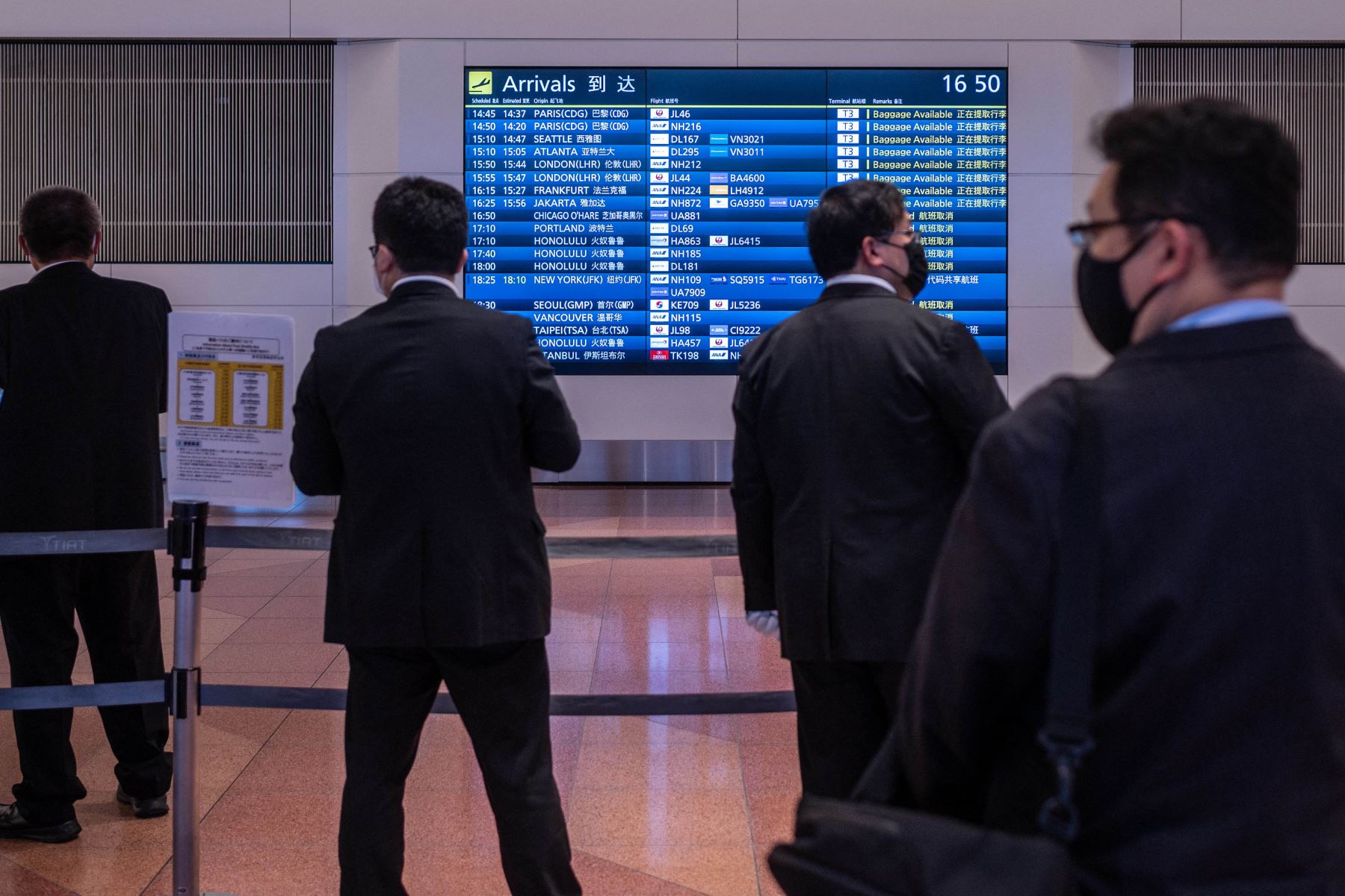 La gente se reúne en la sala de llegadas del aeropuerto internacional Haneda, cuando Japón anunció planes para prohibir a todos los nuevos viajeros extranjeros sobre la variante Omicron de Covid-19. Foto: AFP