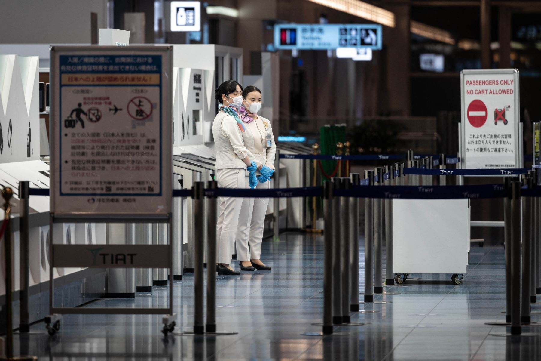 Miembros del personal se paran en la puerta de salida del aeropuerto internacional Haneda de Tokio, cuando Japón anunció planes para prohibir a todos los nuevos viajeros extranjeros sobre la variante Omicron de Covid-19. Foto: AFP