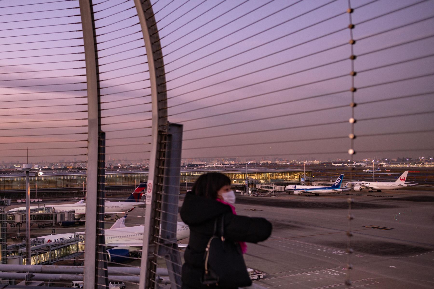 Una mujer mira desde la plataforma de observación del aeropuerto internacional Haneda de Tokio, cuando Japón anunció planes para prohibir a todos los nuevos viajeros extranjeros la variante Omicron de Covid-19. Foto: AFP